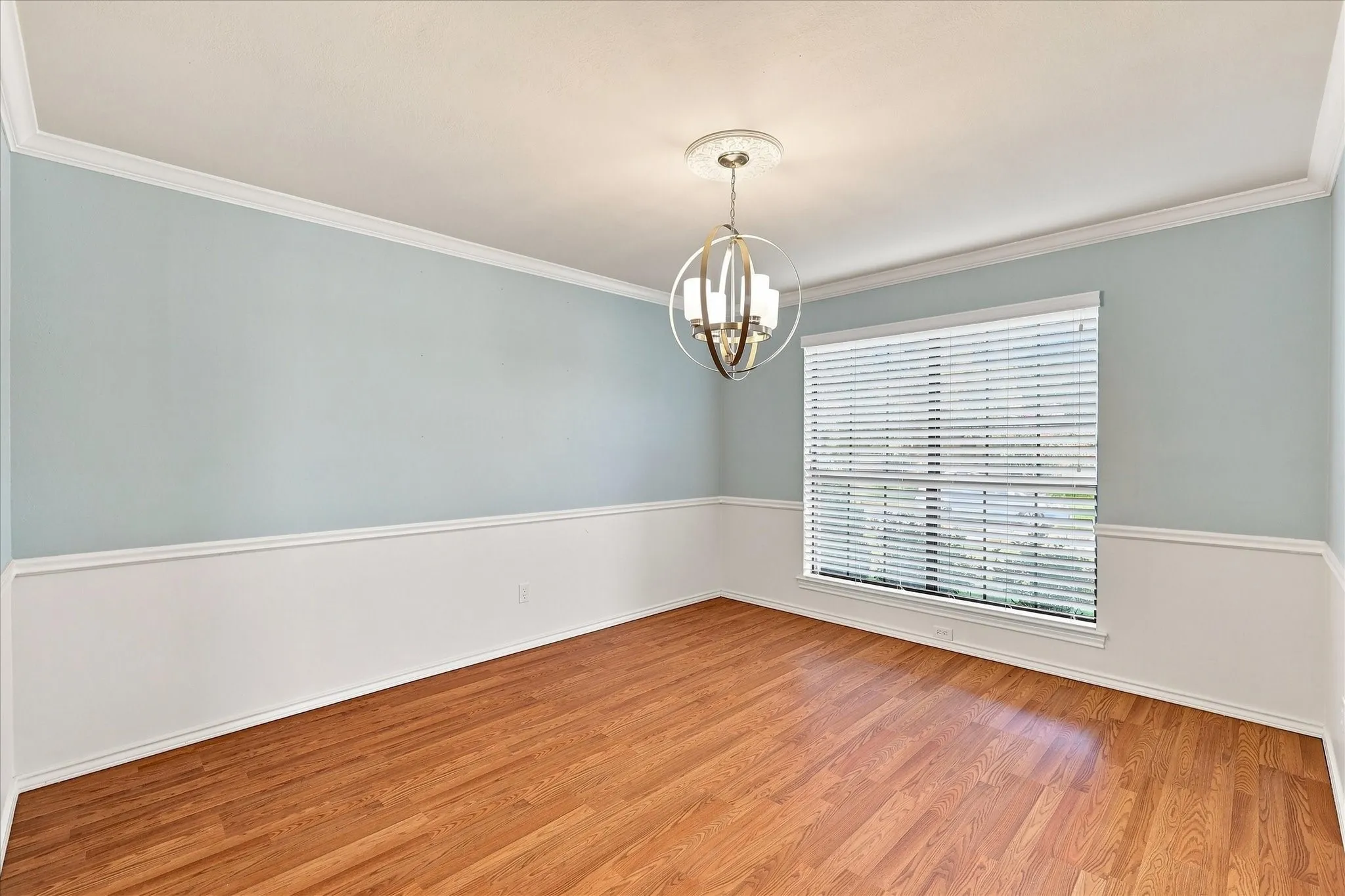 Wood-finish flooring, crown molding, chair rail, and a decorative ceiling medallion