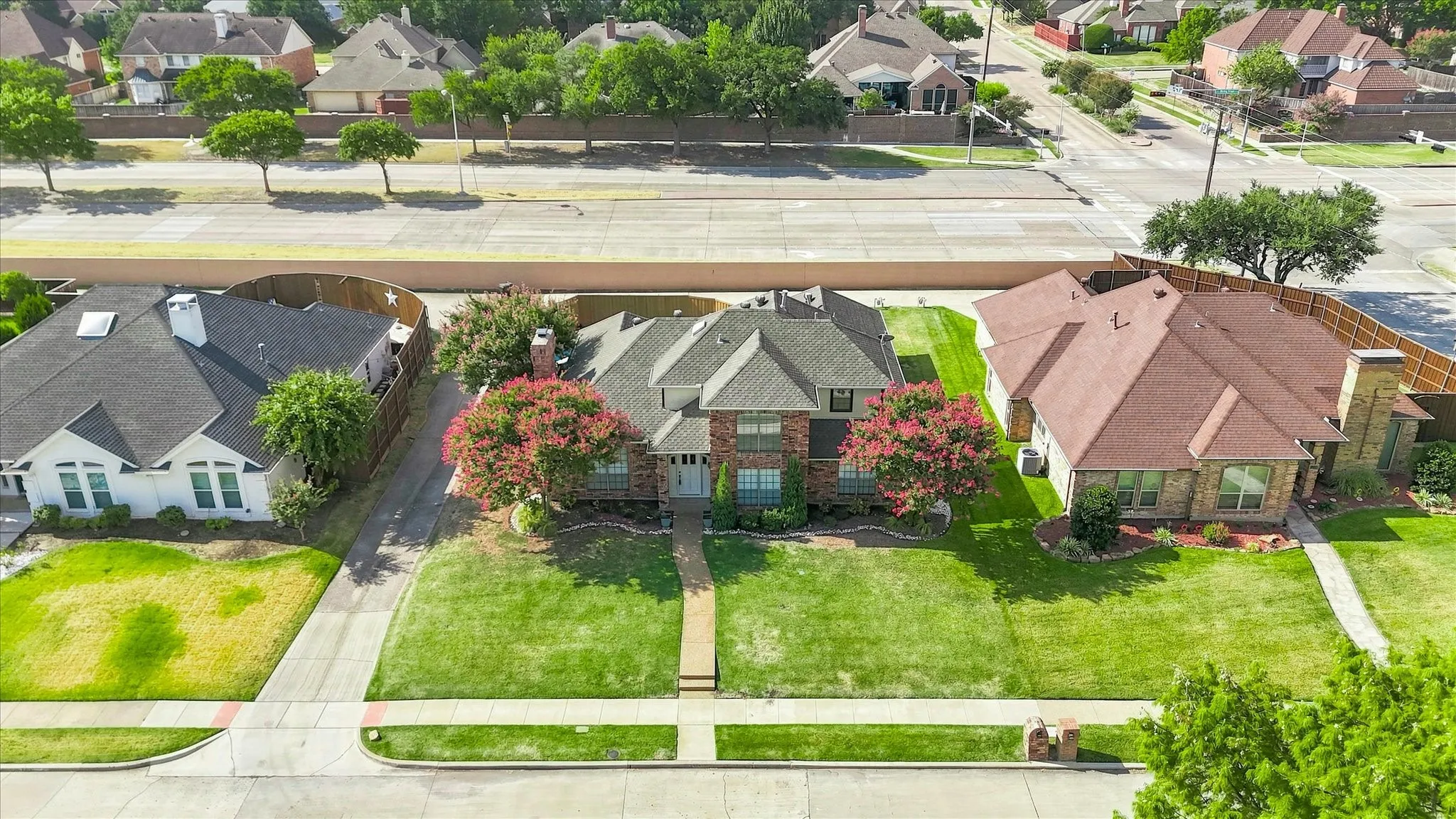 Traditional-style residence featuring a brick facade, mature landscaping, and a manicured lawn