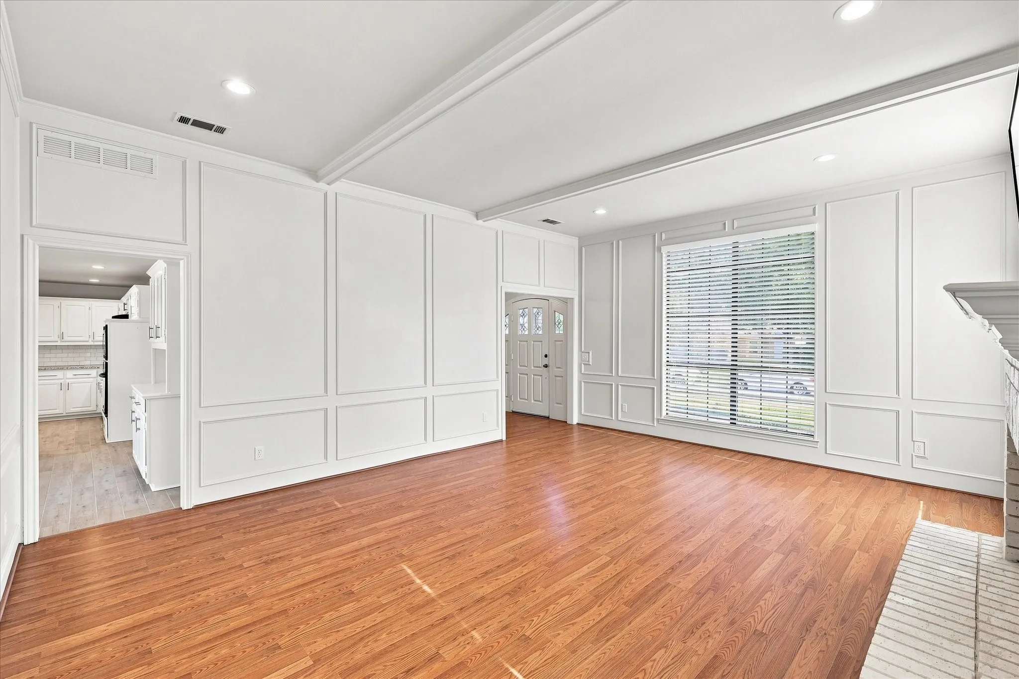 Wood-finish flooring, recessed lighting, decorative wall paneling, large window, and a brick fireplace