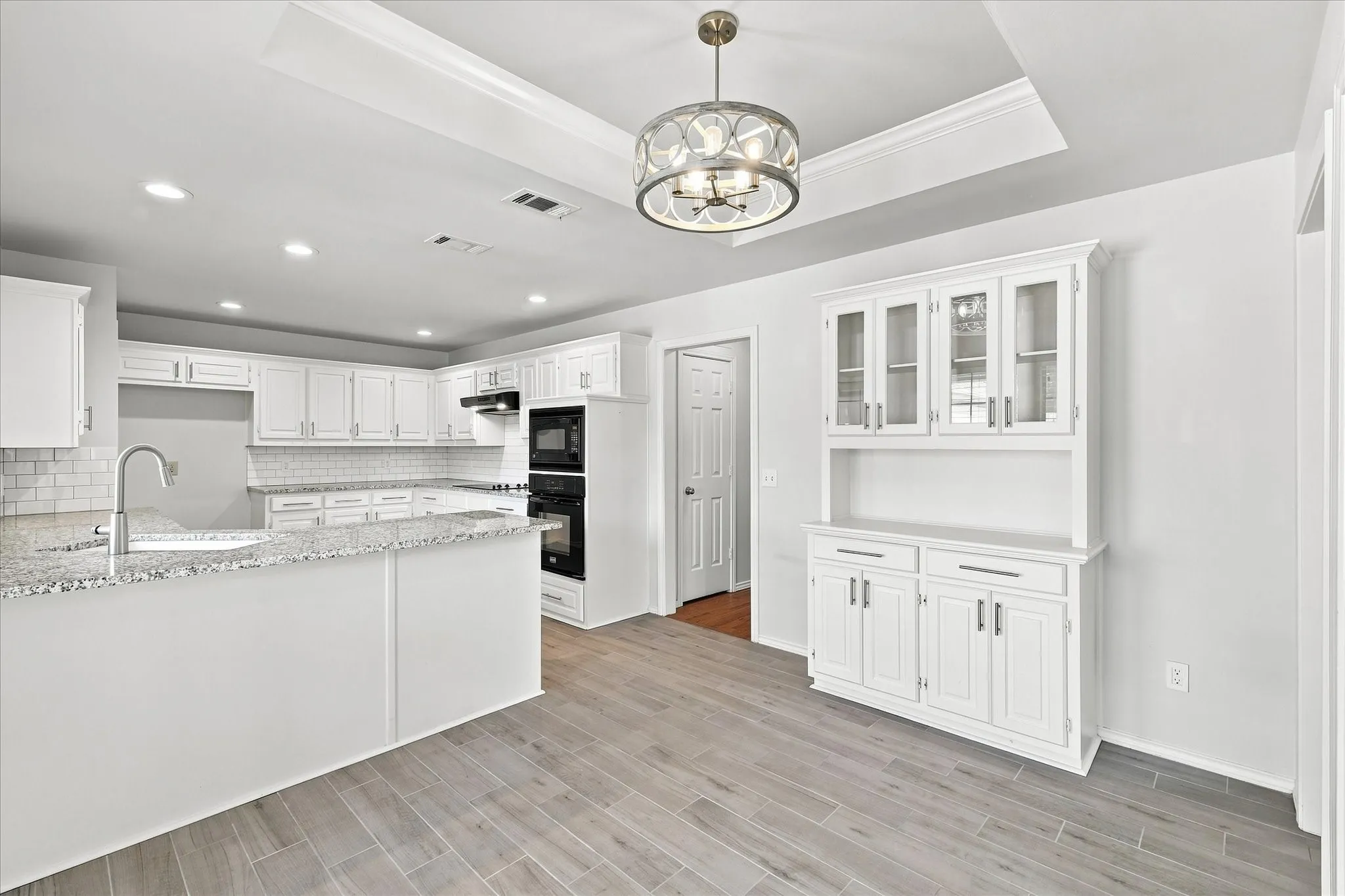 Kitchen featuring white cabinetry, light-toned granite countertops, and a subway tile backsplash