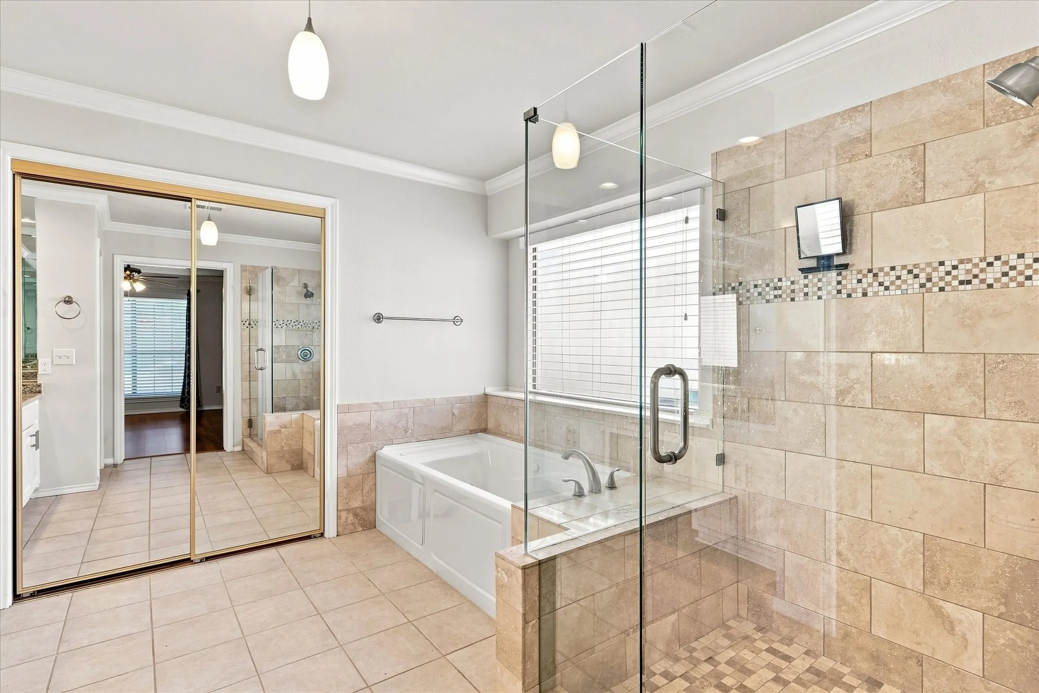 Spacious bathroom featuring a built-in soaking tub, a walk-in shower with natural stone-look tile, glass shower enclosure, and a window with blinds
