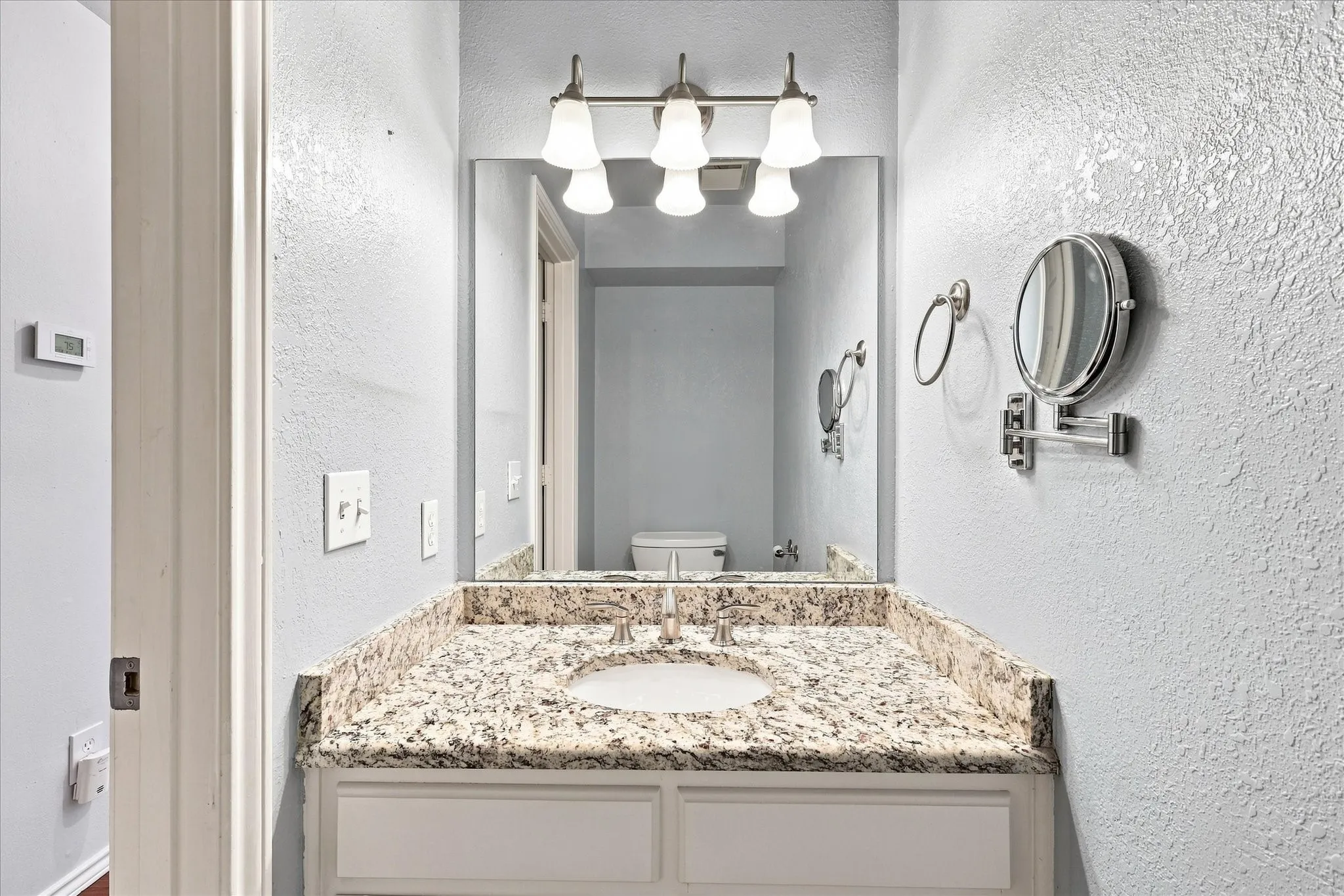 Vanity with a granite countertop, undermount sink, and brushed nickel faucet