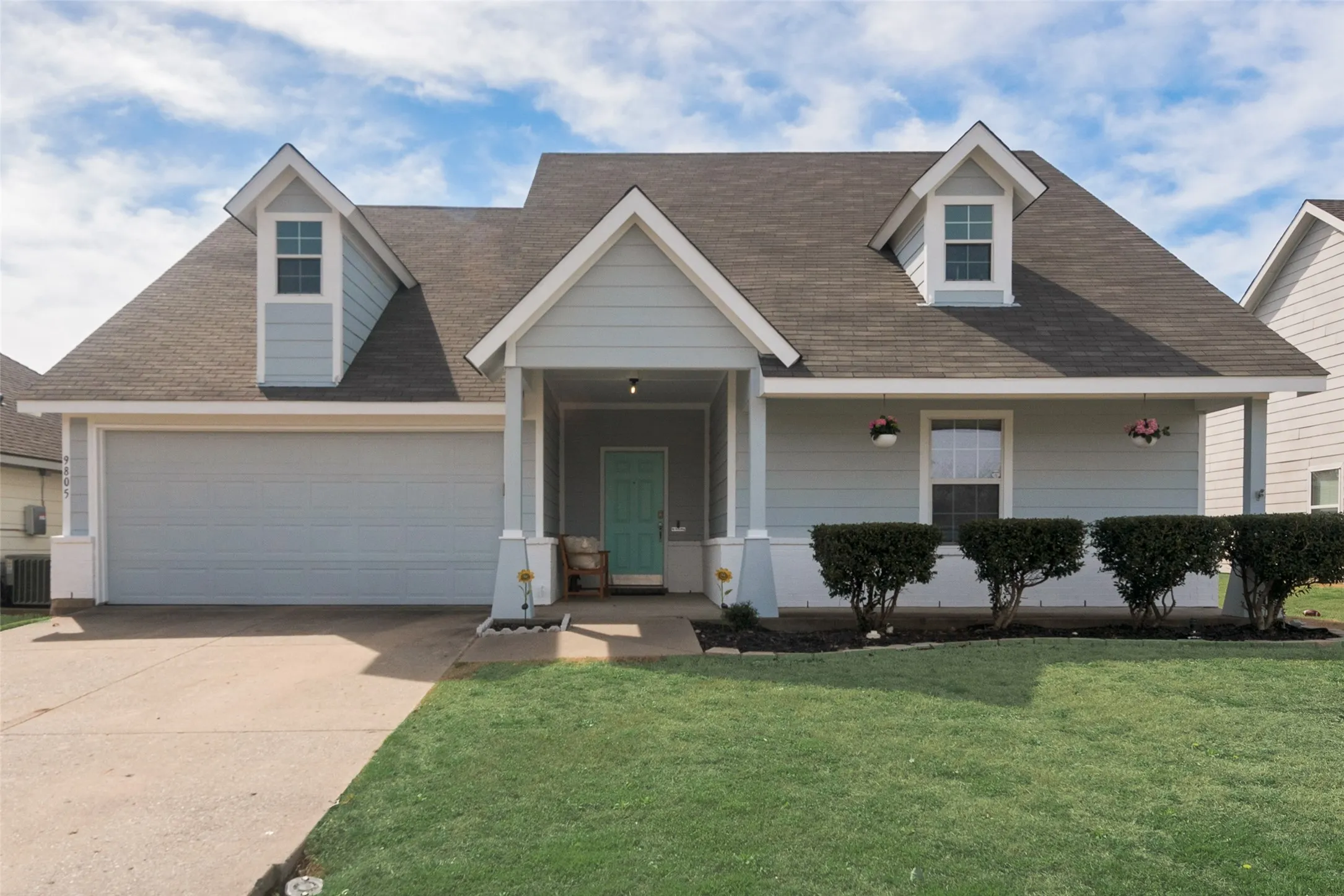 Light blue siding with white trim and a covered front porch featuring a vibrant teal entry door