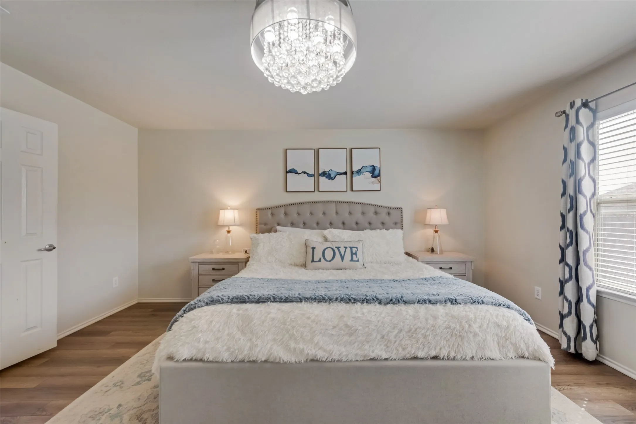 Wood-finish flooring, recessed lighting, white panel door, and a crystal chandelier