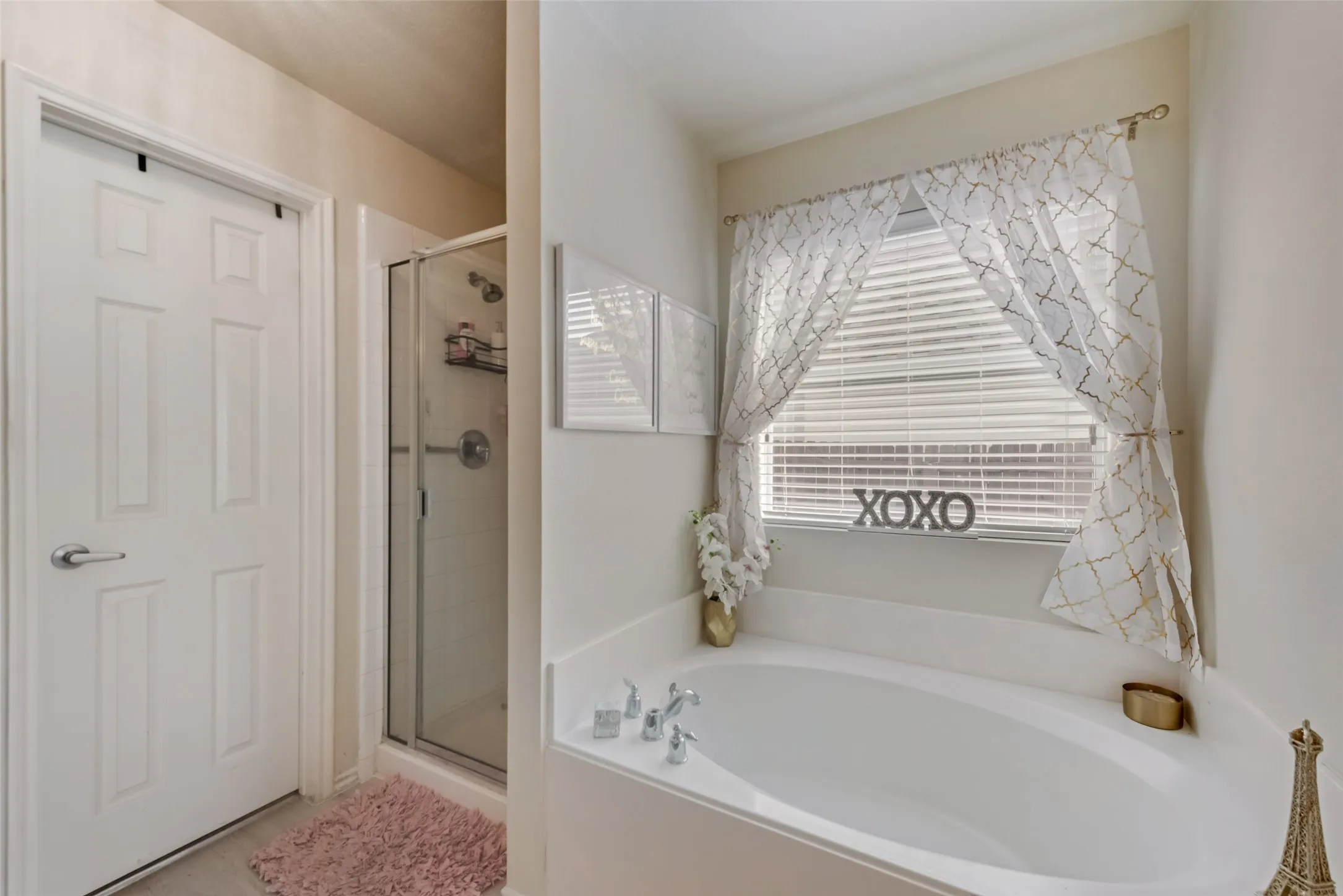 Built-in soaking tub with deck-mounted fixtures, enclosed shower with glass door, and solid core door