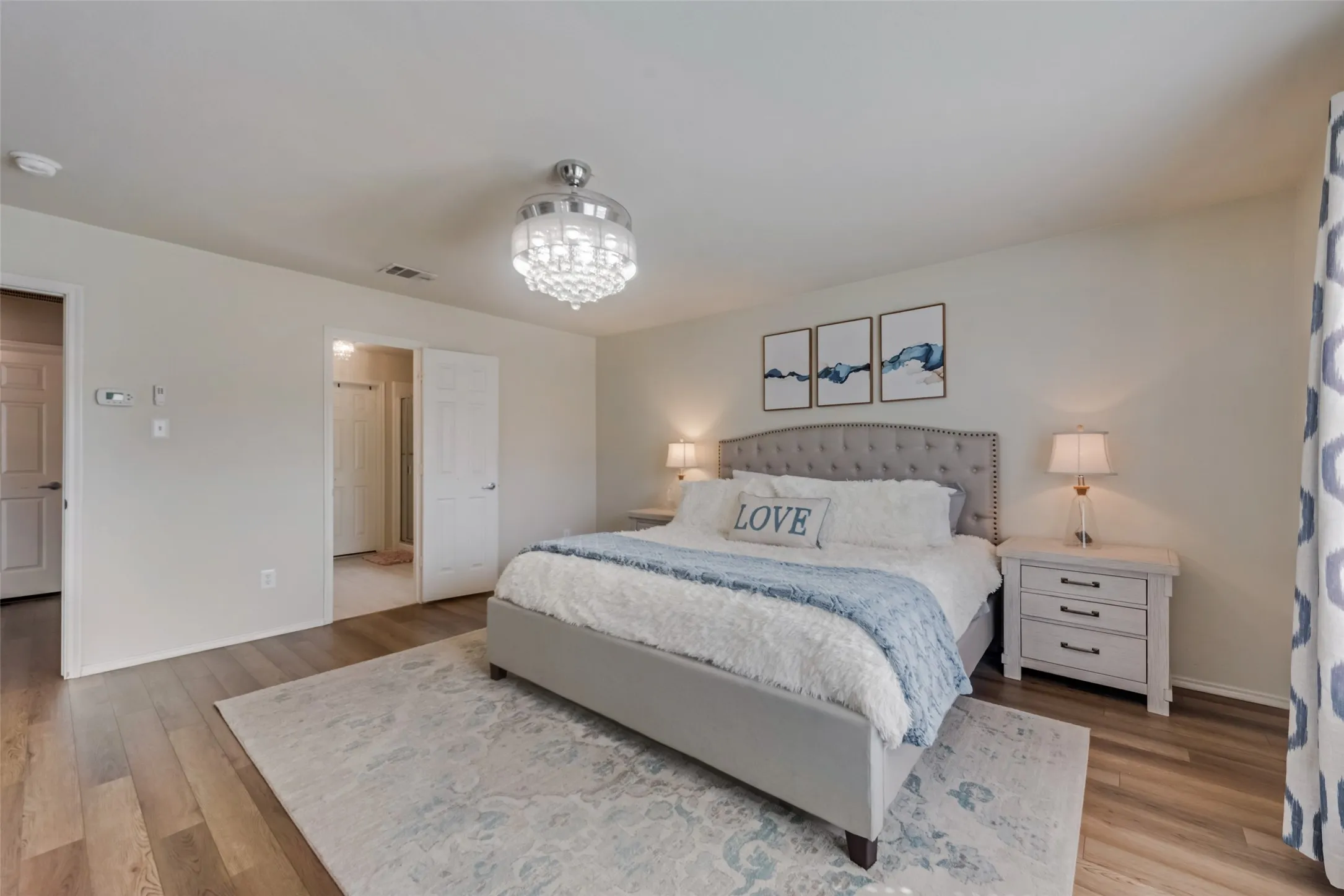Wood-finish flooring, white paneled doors, and a chandelier with a polished chrome finish