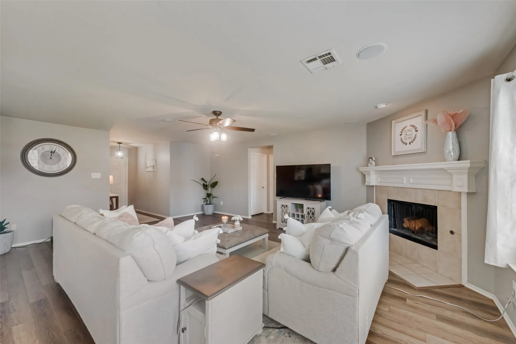 Wood-finish flooring throughout, featuring a corner fireplace with a tiled hearth and a decorative mantel