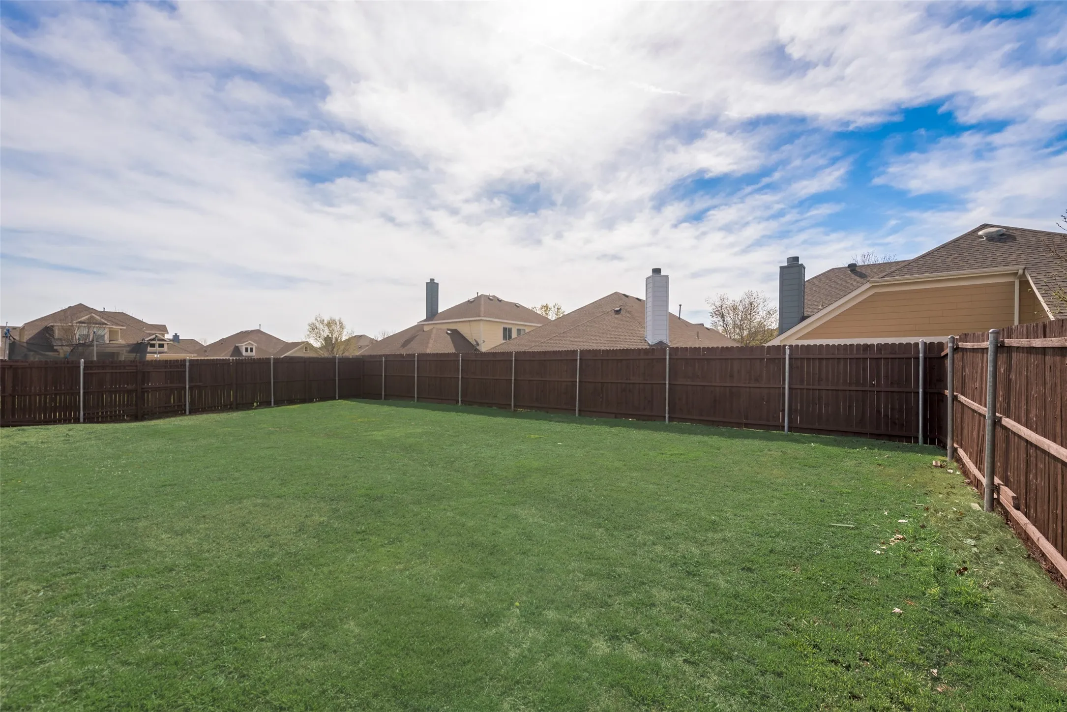 Expansive grassy yard enclosed by a stained wood privacy fence