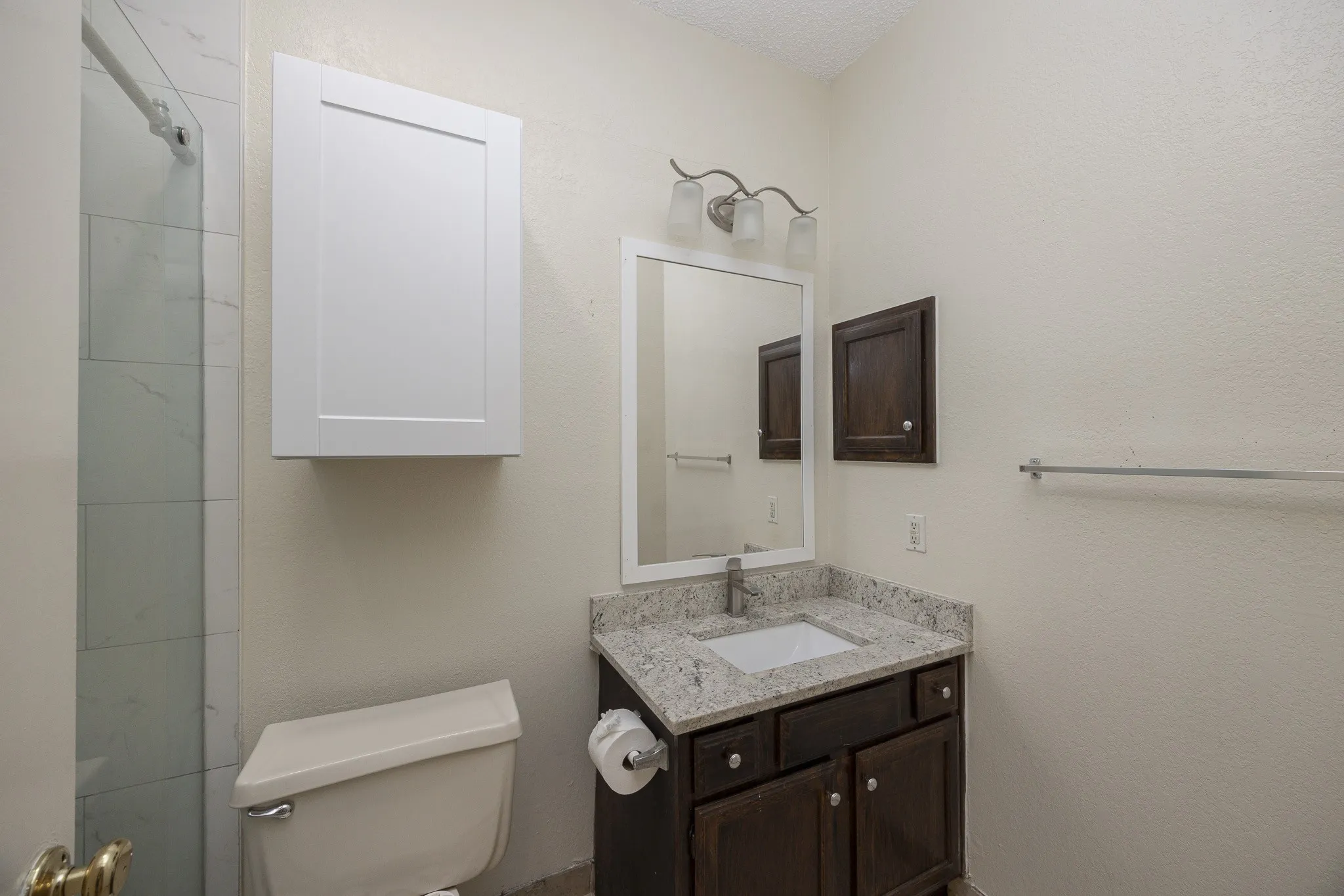 Granite-finish countertop with an undermount sink, dark wood-finish vanity, and a wall-mounted medicine cabinet