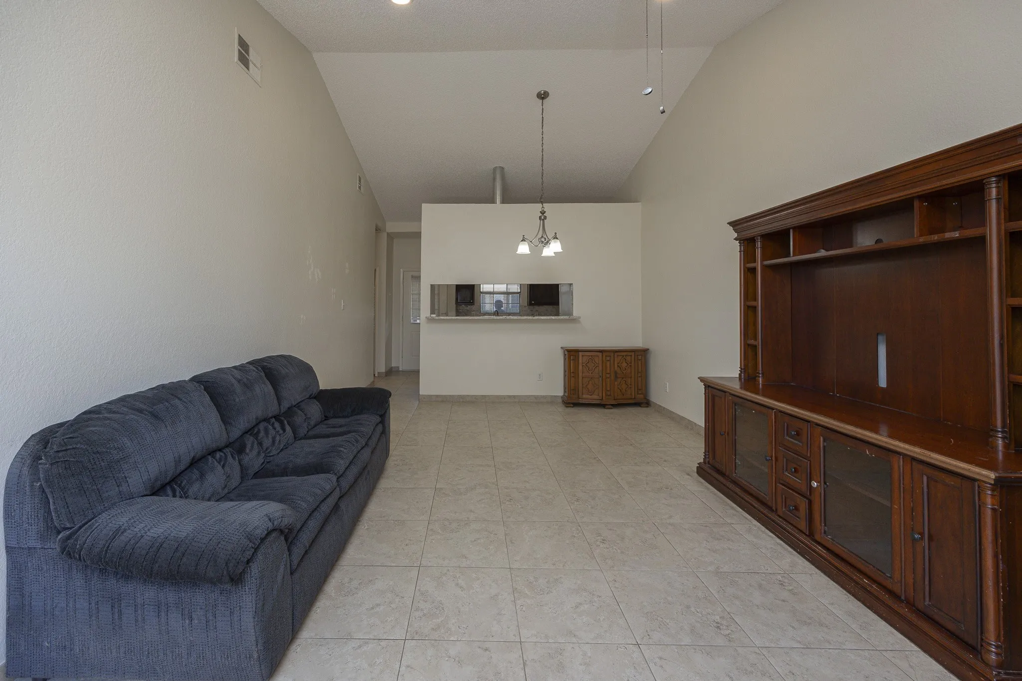 Vaulted ceiling, recessed lighting, tile flooring, and a pass-through window to the kitchen