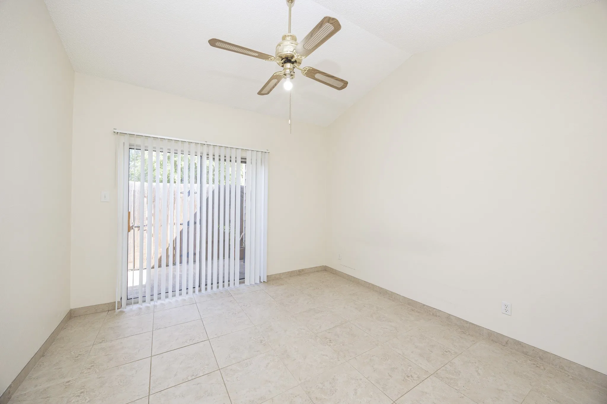 Vaulted ceiling with a ceiling fan, sliding glass door, vertical blinds, and tile flooring