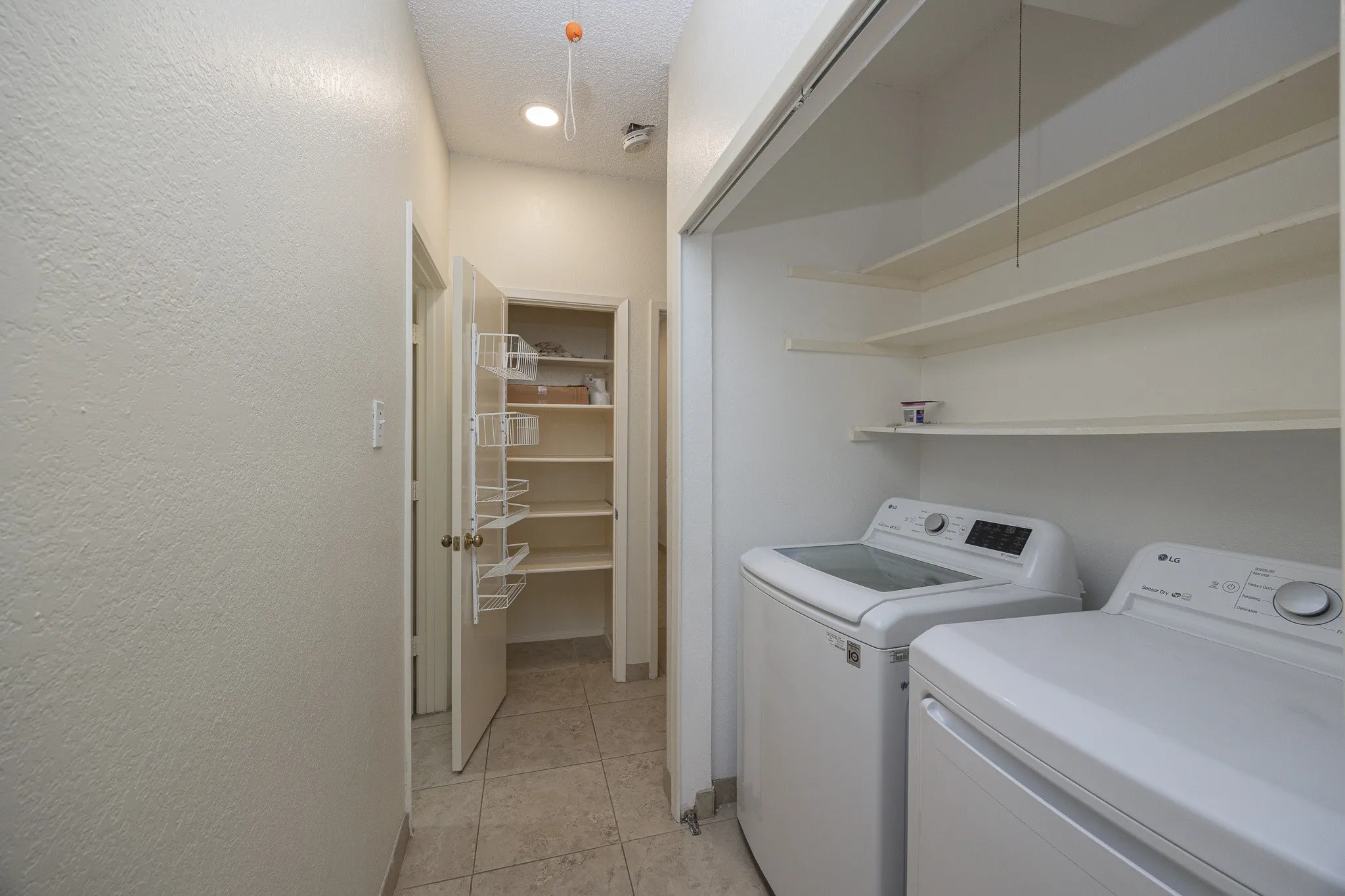 Laundry area with built-in shelving and an adjacent pantry featuring multiple storage shelves