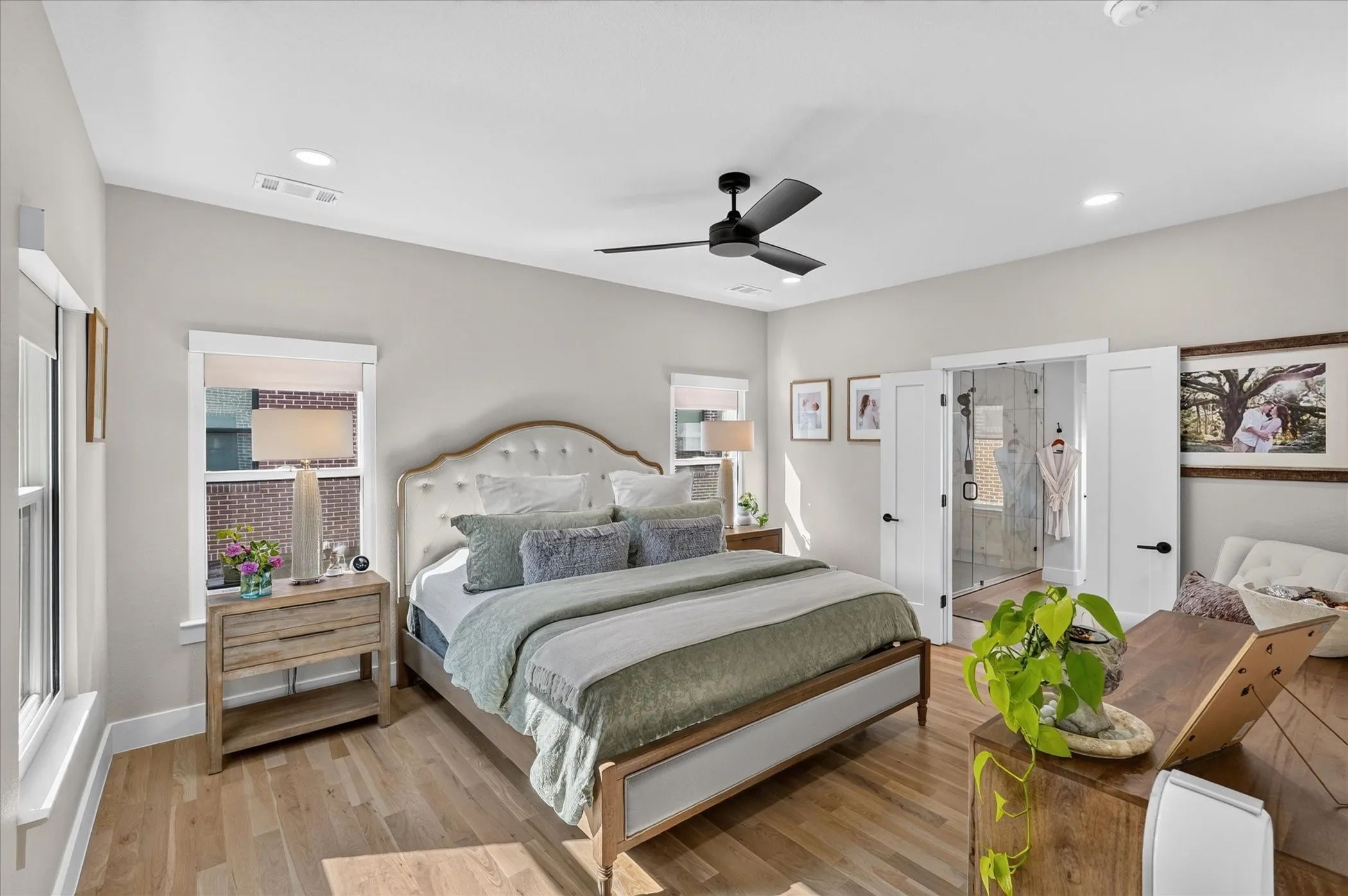 Spacious bedroom with wood-finish flooring, recessed lighting, ceiling fan, and double doors opening to a shower enclosure