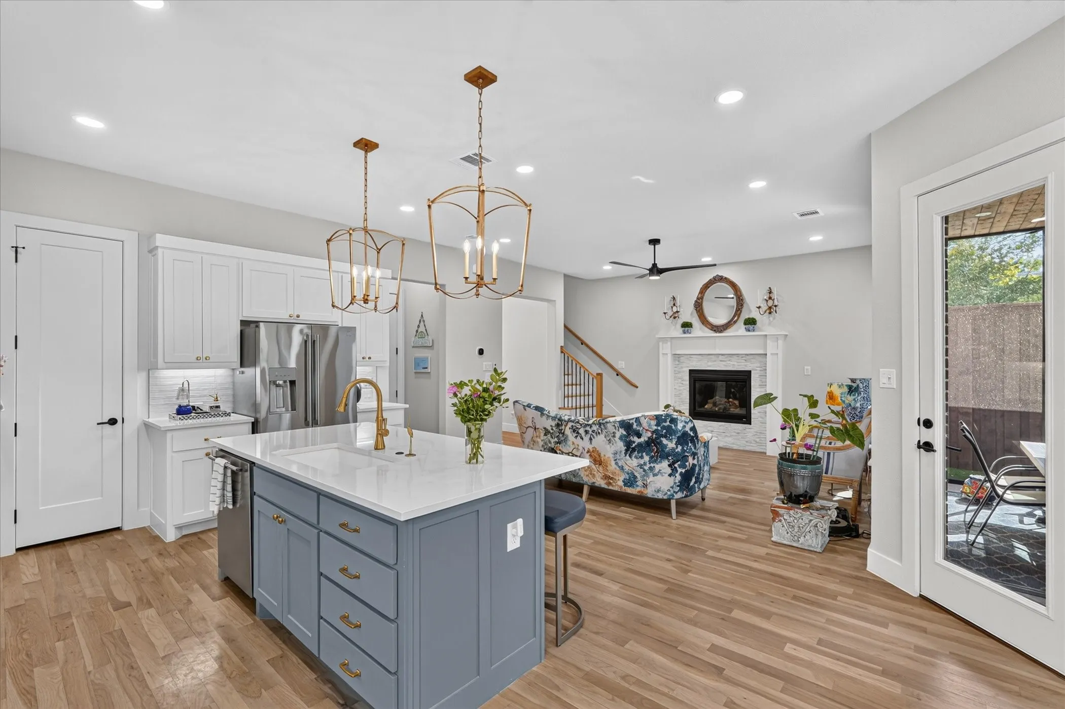Open-concept living area featuring wood-finish flooring, a kitchen island with seating, white shaker cabinetry, stainless steel appliances, and recessed lighting