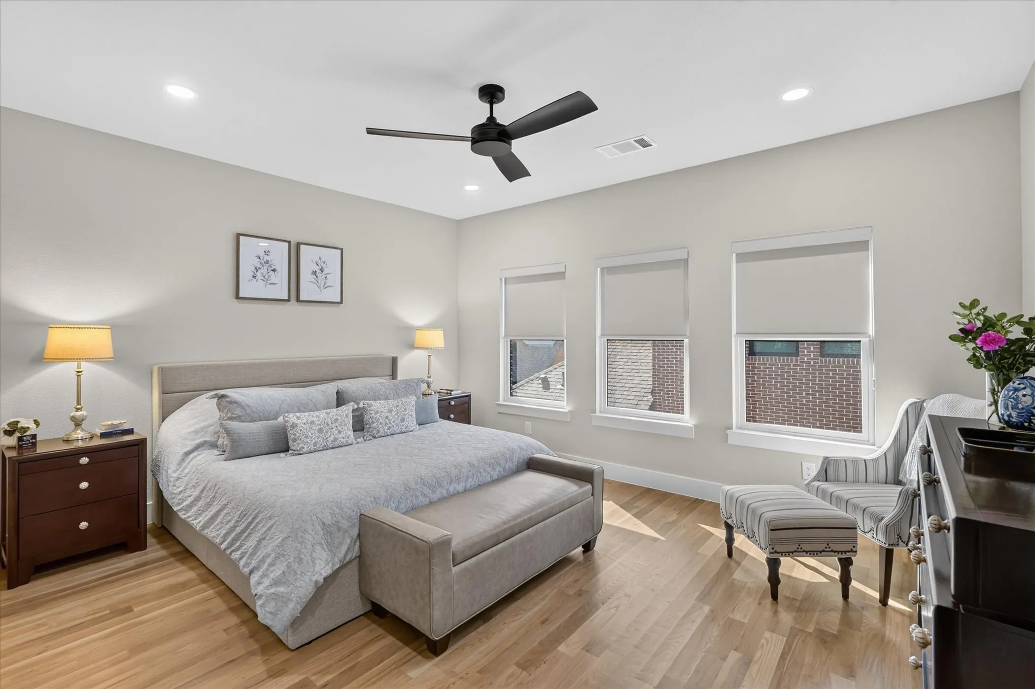 Recessed lighting, wood-finish flooring, three windows with roller shades, and a ceiling fan