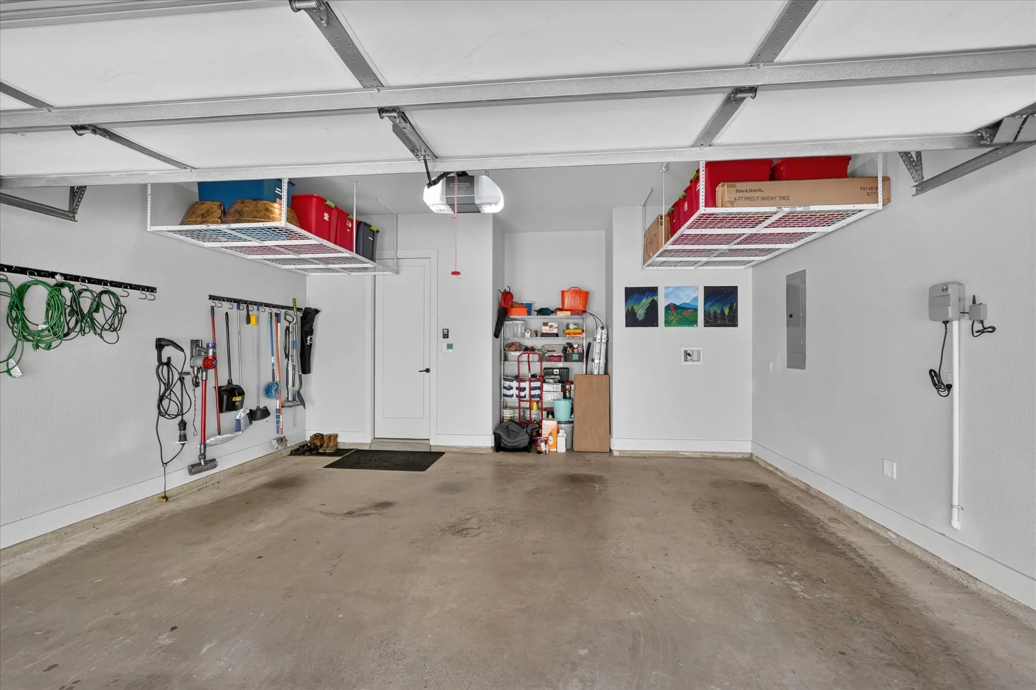Spacious garage featuring concrete flooring and two overhead storage racks
