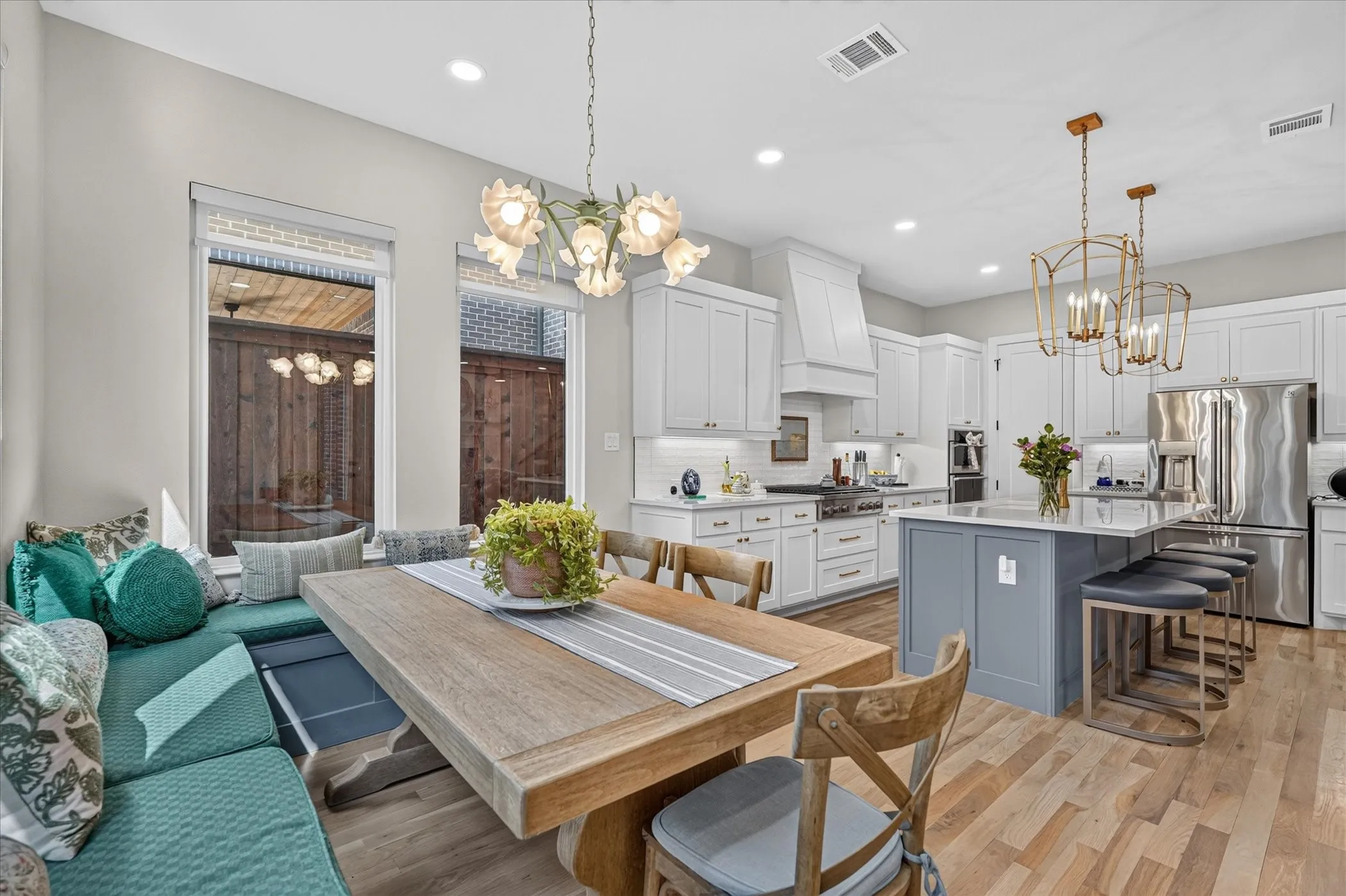 Hardwood-style flooring, built-in banquette seating, kitchen island with seating, stainless steel appliances, and white cabinetry