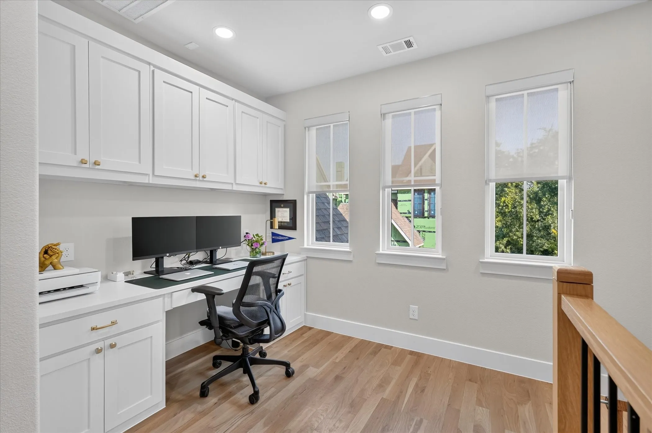 Built-in desk with extensive white cabinetry, recessed lighting, and wood-finish flooring