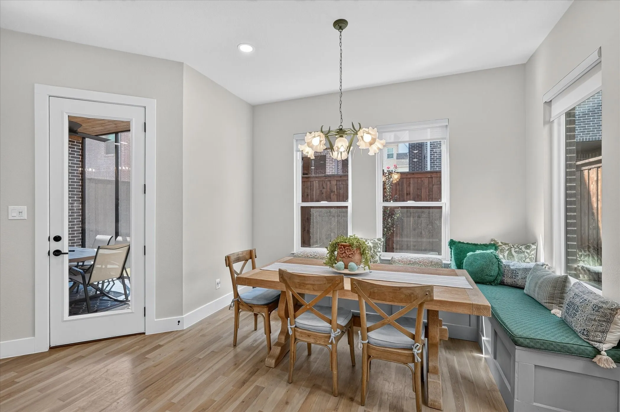 Light wood-finish flooring, built-in window seating, multiple windows, recessed lighting, and a glass-paneled door