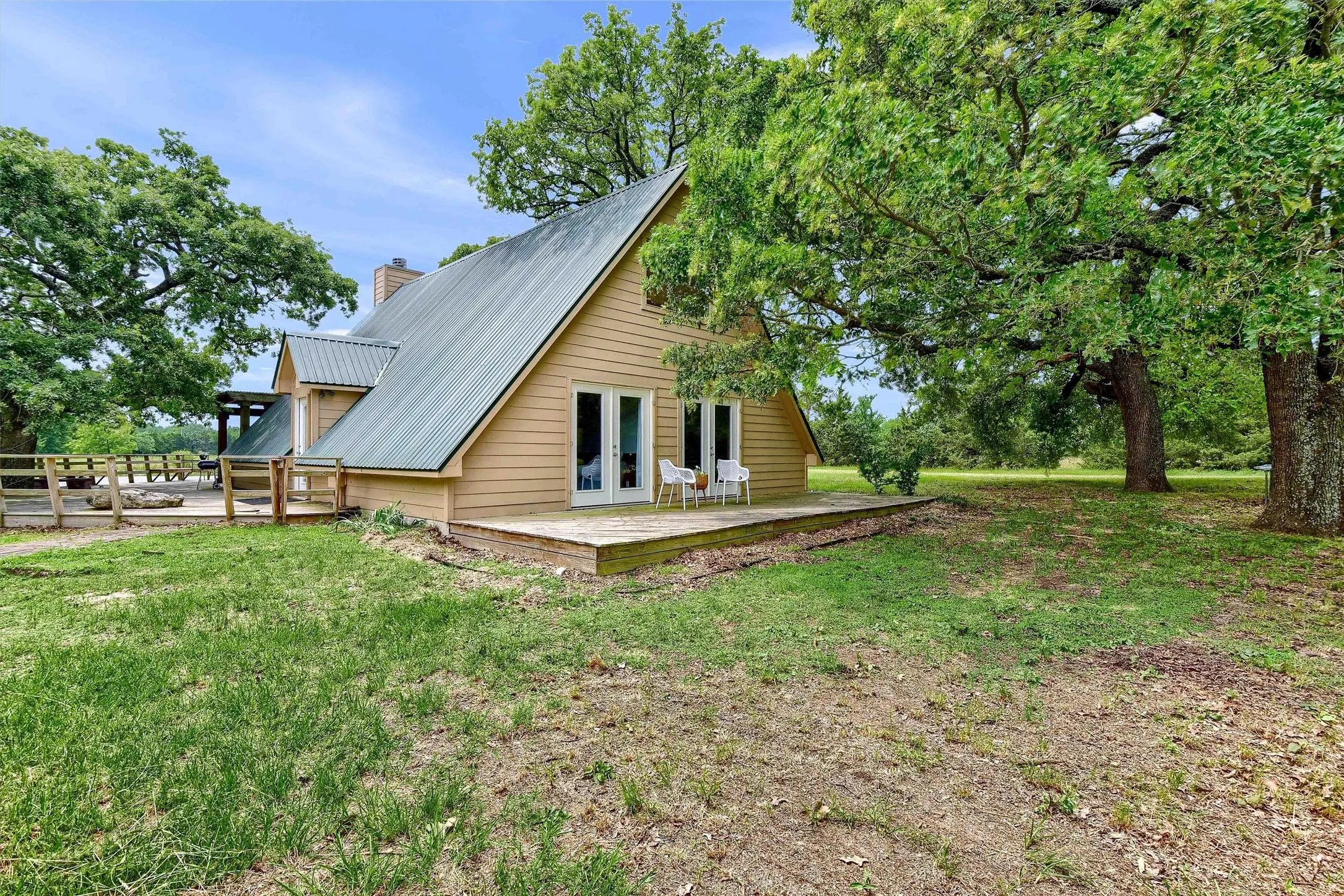 View of property exterior featuring french doors, a wooden deck, and a yard