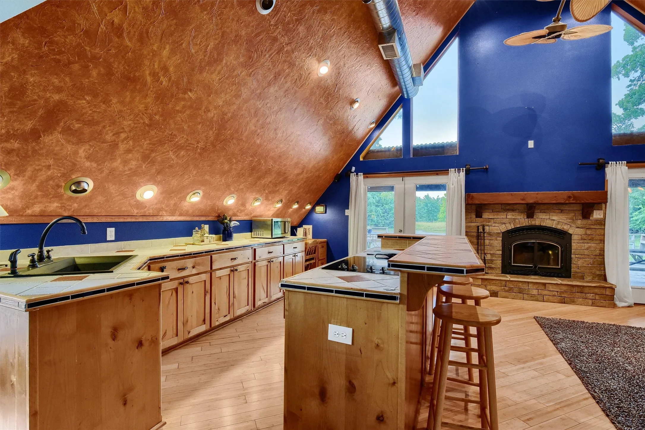 Kitchen featuring light hardwood / wood-style flooring, ceiling fan, tile counters, sink, and lofted ceiling