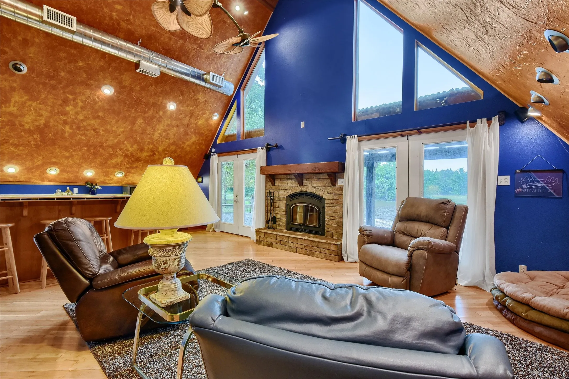 Living room with high vaulted ceiling, french doors, hardwood / wood-style flooring, and a fireplace