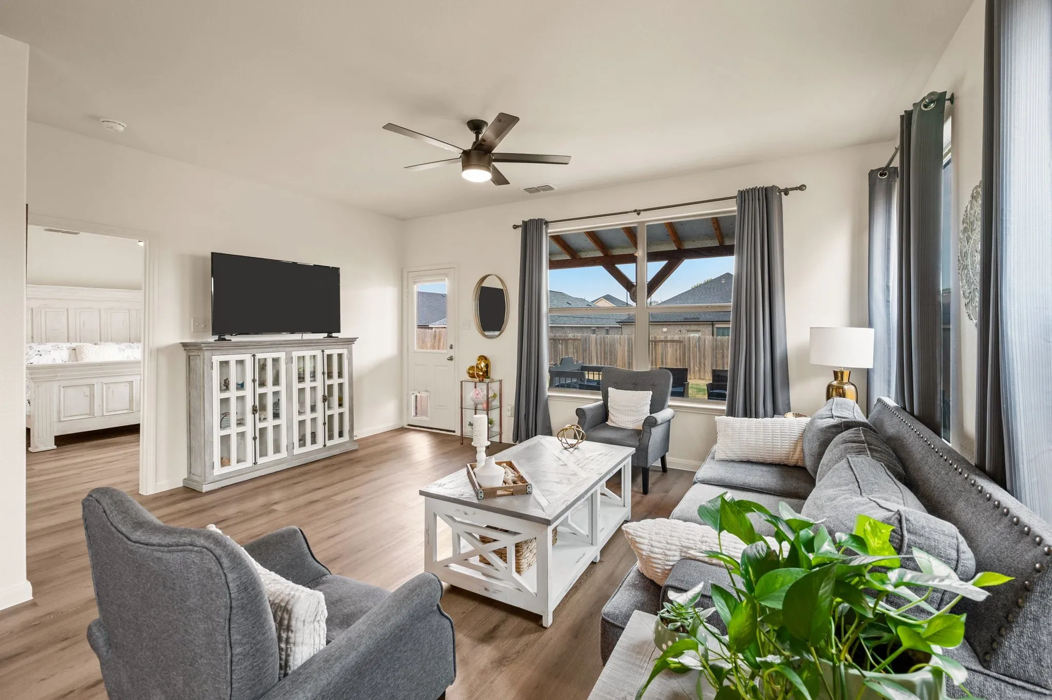 Wood-finish flooring throughout, ceiling fan light fixture, large window, and a rear exterior door