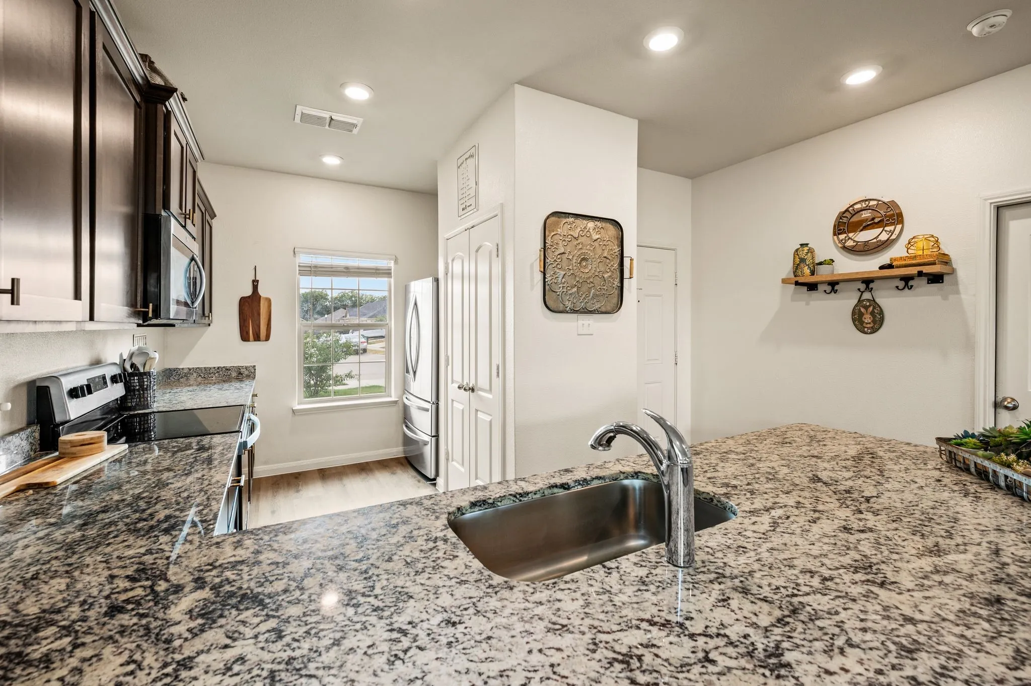 Kitchen featuring granite countertops, dark wood-finish cabinetry, stainless steel appliances, and wood-finish flooring