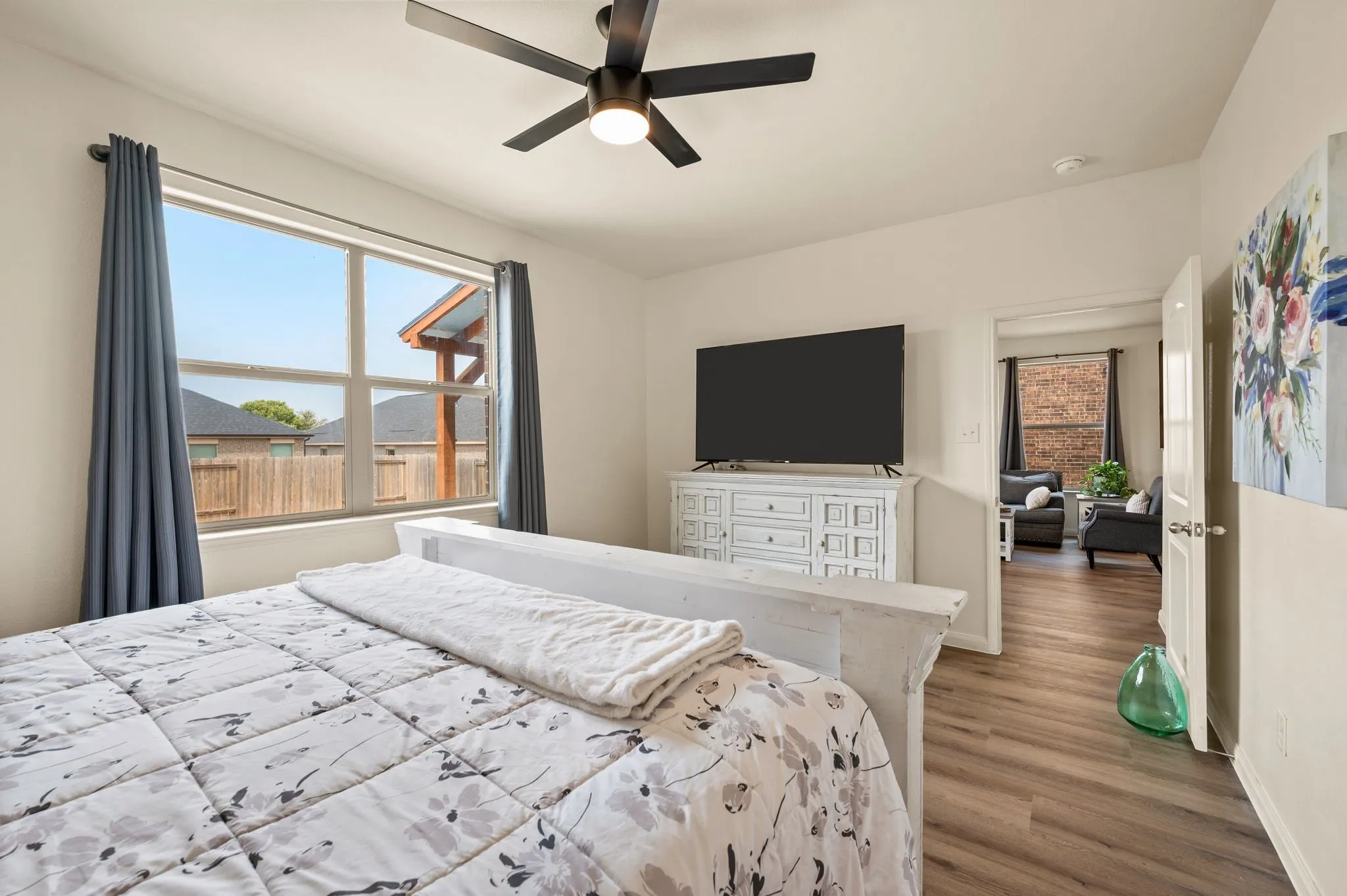 Spacious room featuring wood-finish flooring, a contemporary ceiling fan, and a large window