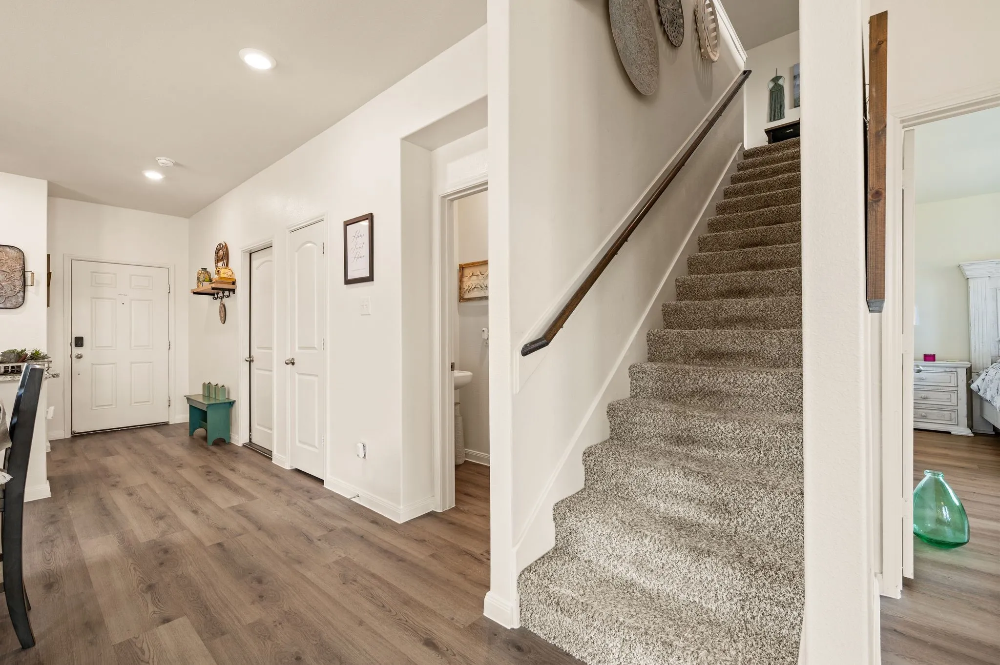 Wood-finish flooring, white paneled doors, carpeted staircase, and recessed lighting