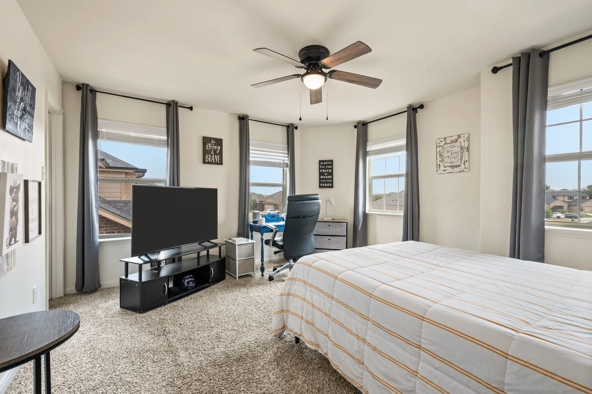 Carpeted room featuring multiple windows, a ceiling fan with light, and a walk in closet .