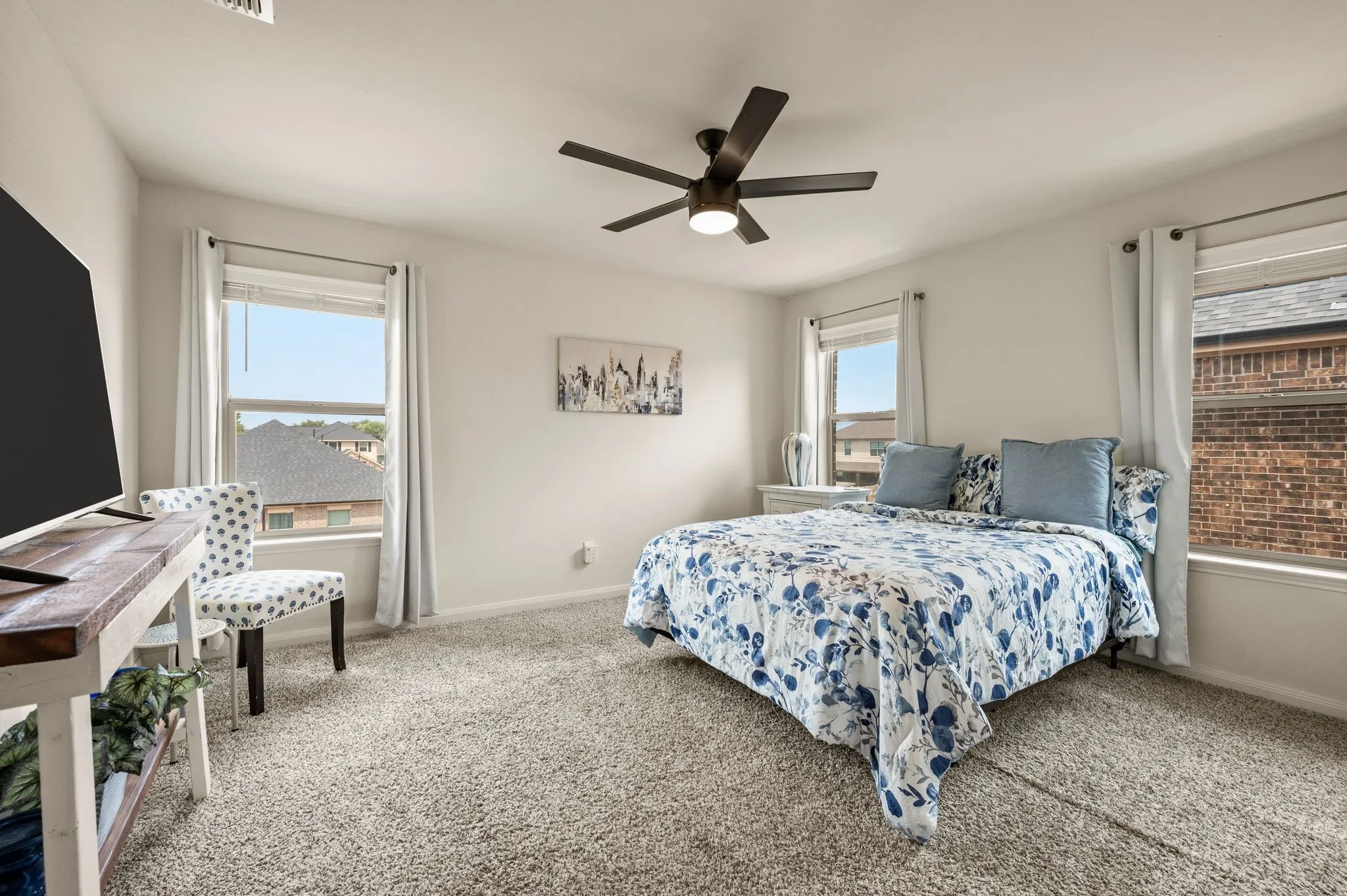 Spacious room featuring light-colored walls, carpeted flooring, and multiple windows