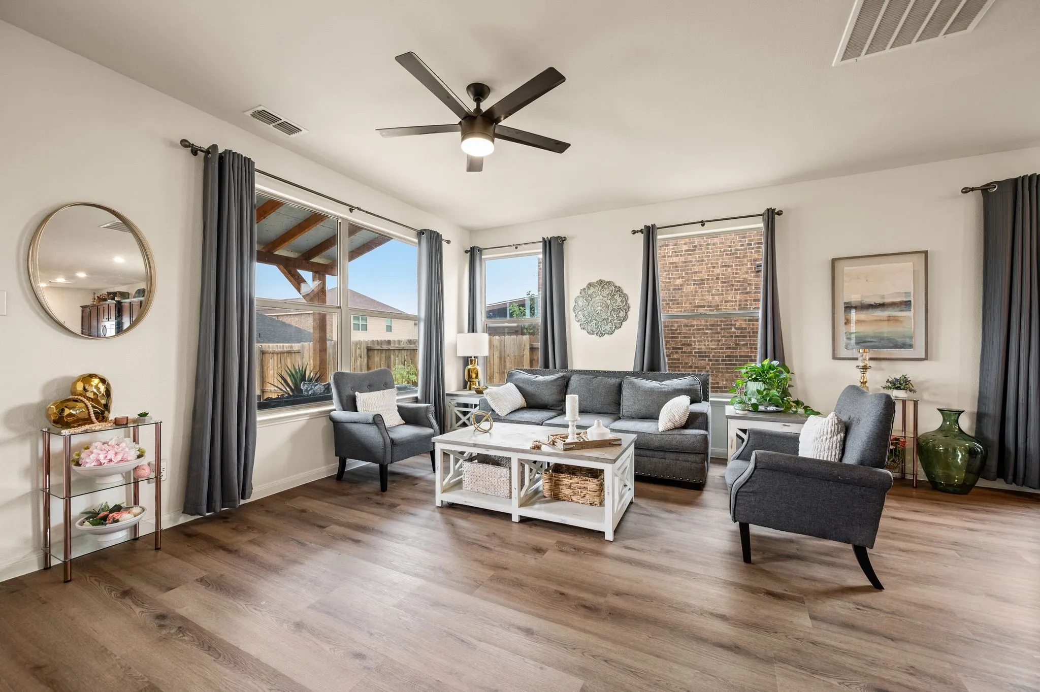 Wood-finish flooring throughout, ceiling fan with integrated lighting, multiple windows providing natural light, and white walls