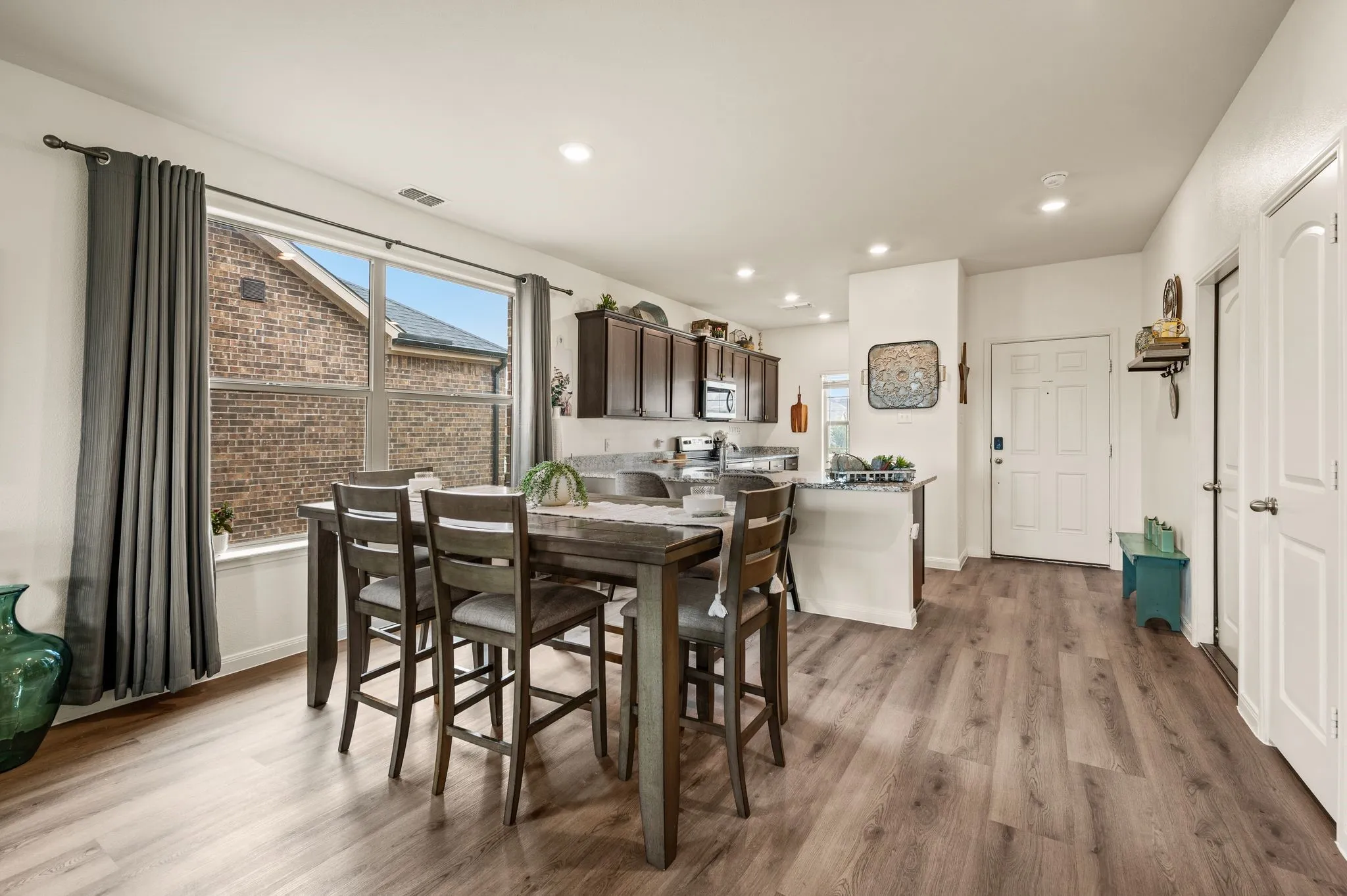 Kitchen and dining area featuring wood-finish flooring, recessed lighting, and dark wood cabinetry