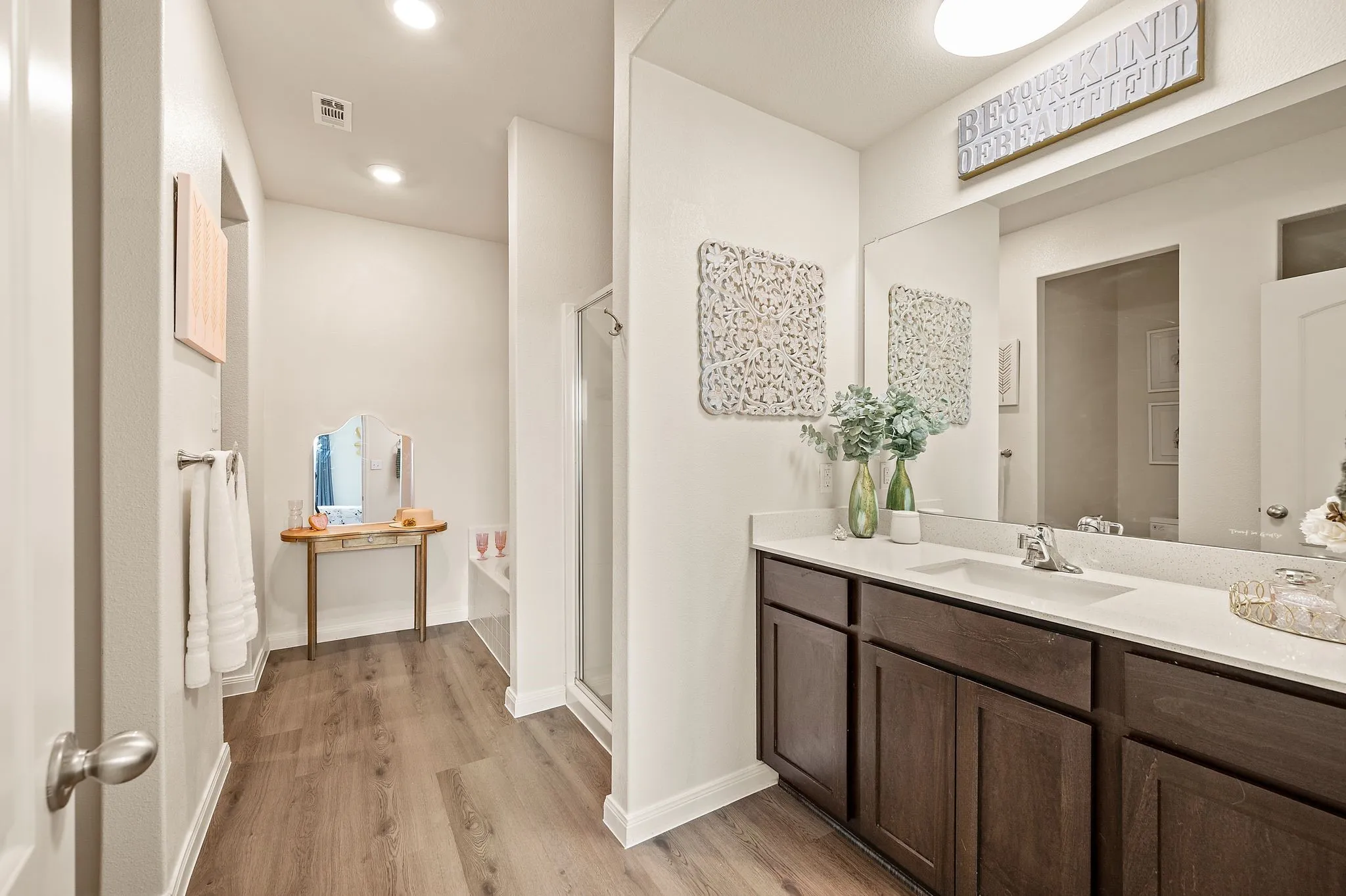 Dual-sink vanity with a light-toned countertop, dark wood-finish cabinetry, and a large mirror