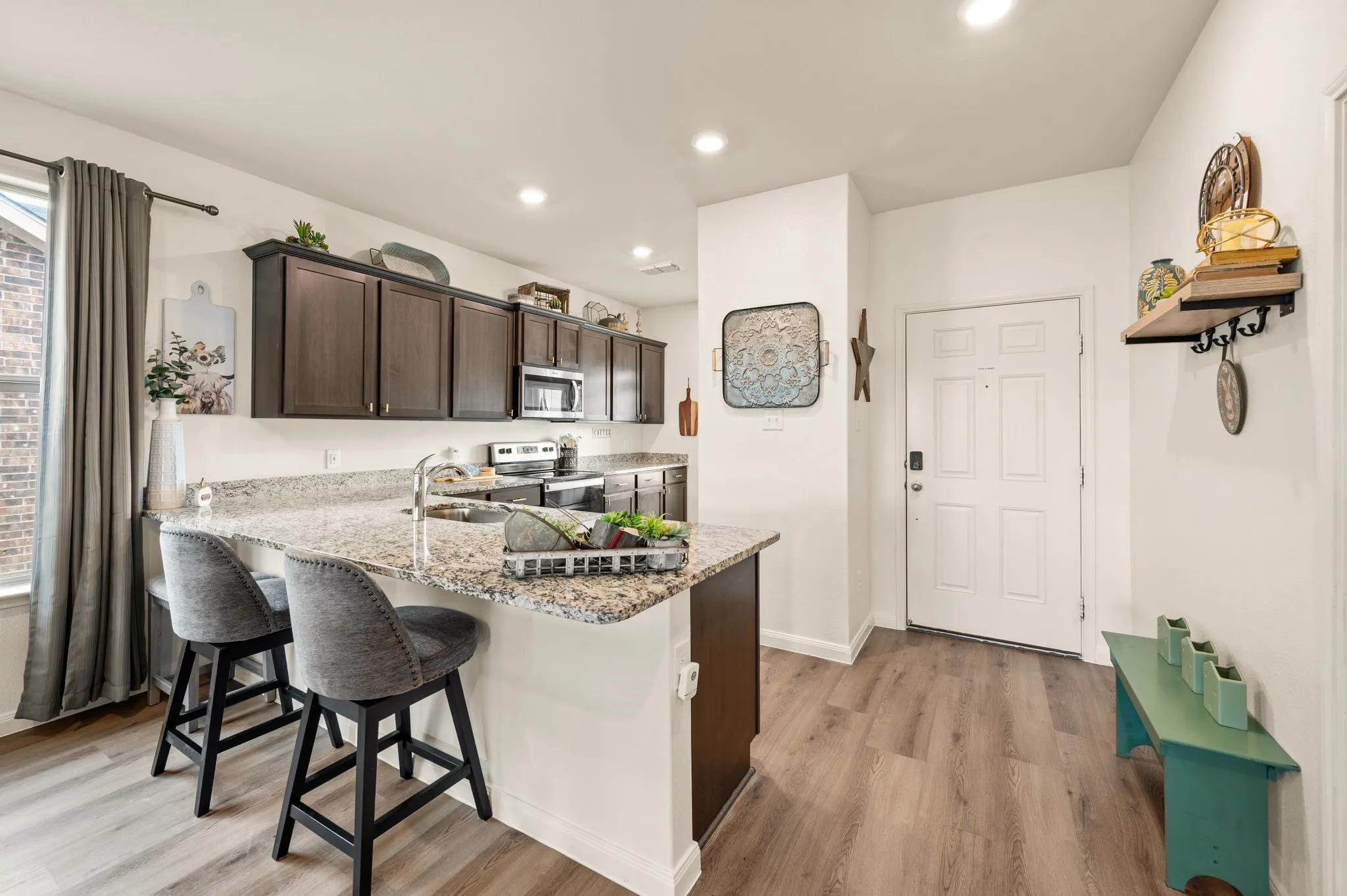 Kitchen featuring dark wood-finish cabinetry, stainless steel appliances, granite countertops, and wood-finish flooring