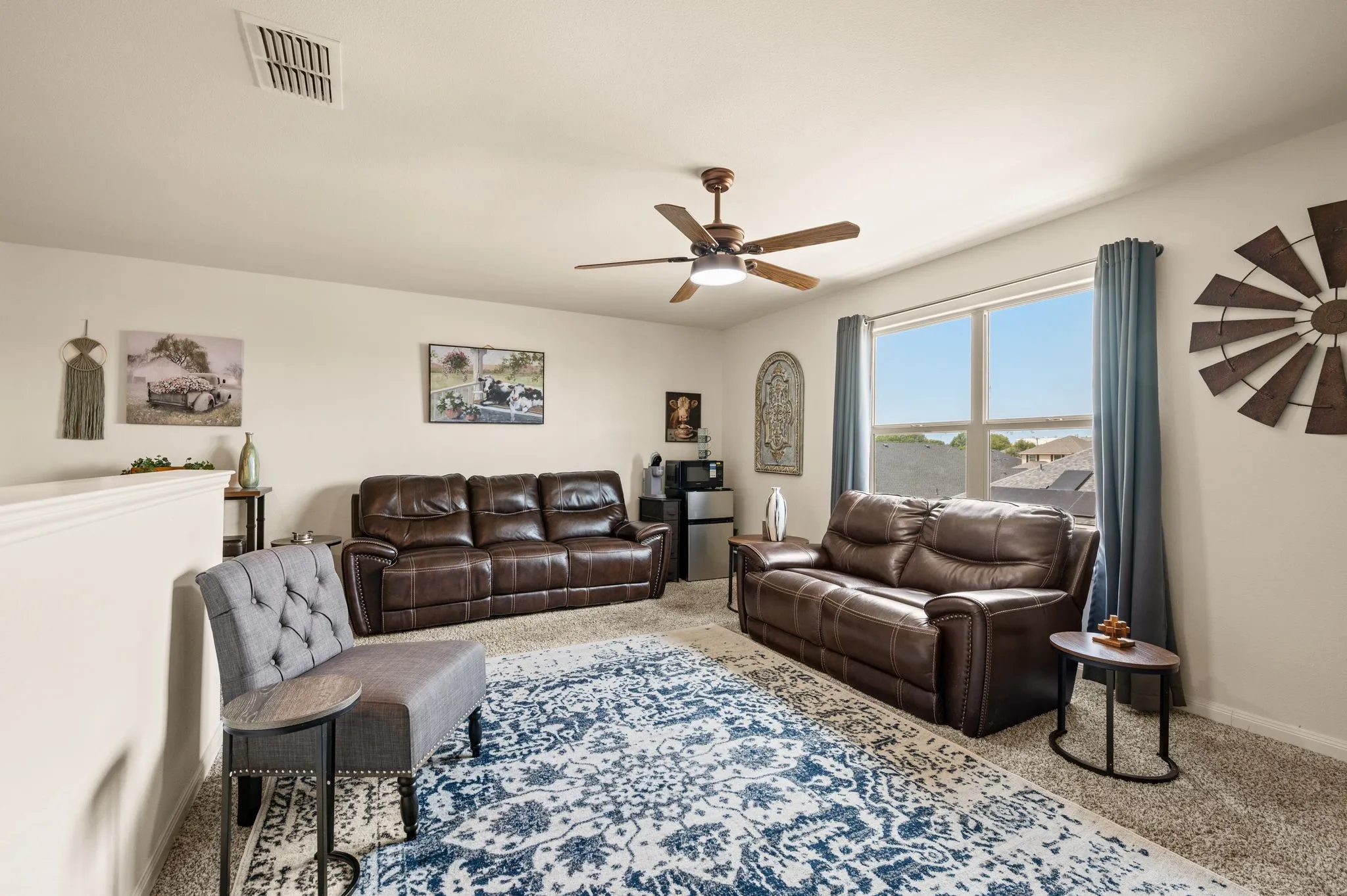 Upstairs living room or flex space. Carpeted flooring, ceiling fan with integrated lighting, and multiple windows providing natural light