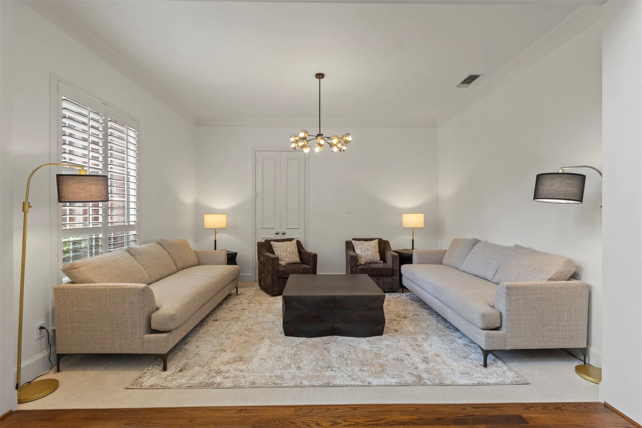 Bright interior with crown molding, wood-finish flooring, plantation shutters, and a modern chandelier