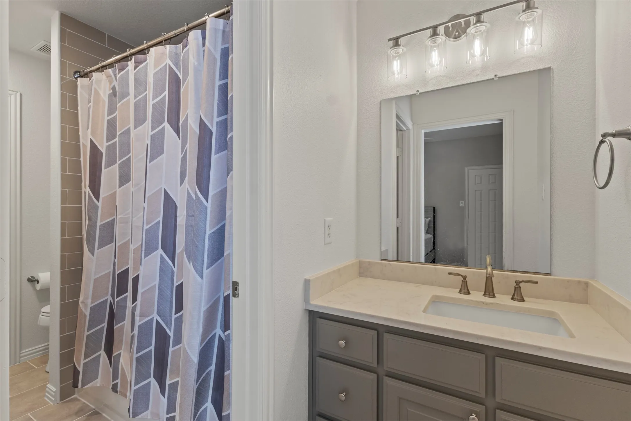 Vanity with an integrated sink and light-toned countertop, brushed brass-finish faucet, and a wall-mounted mirror