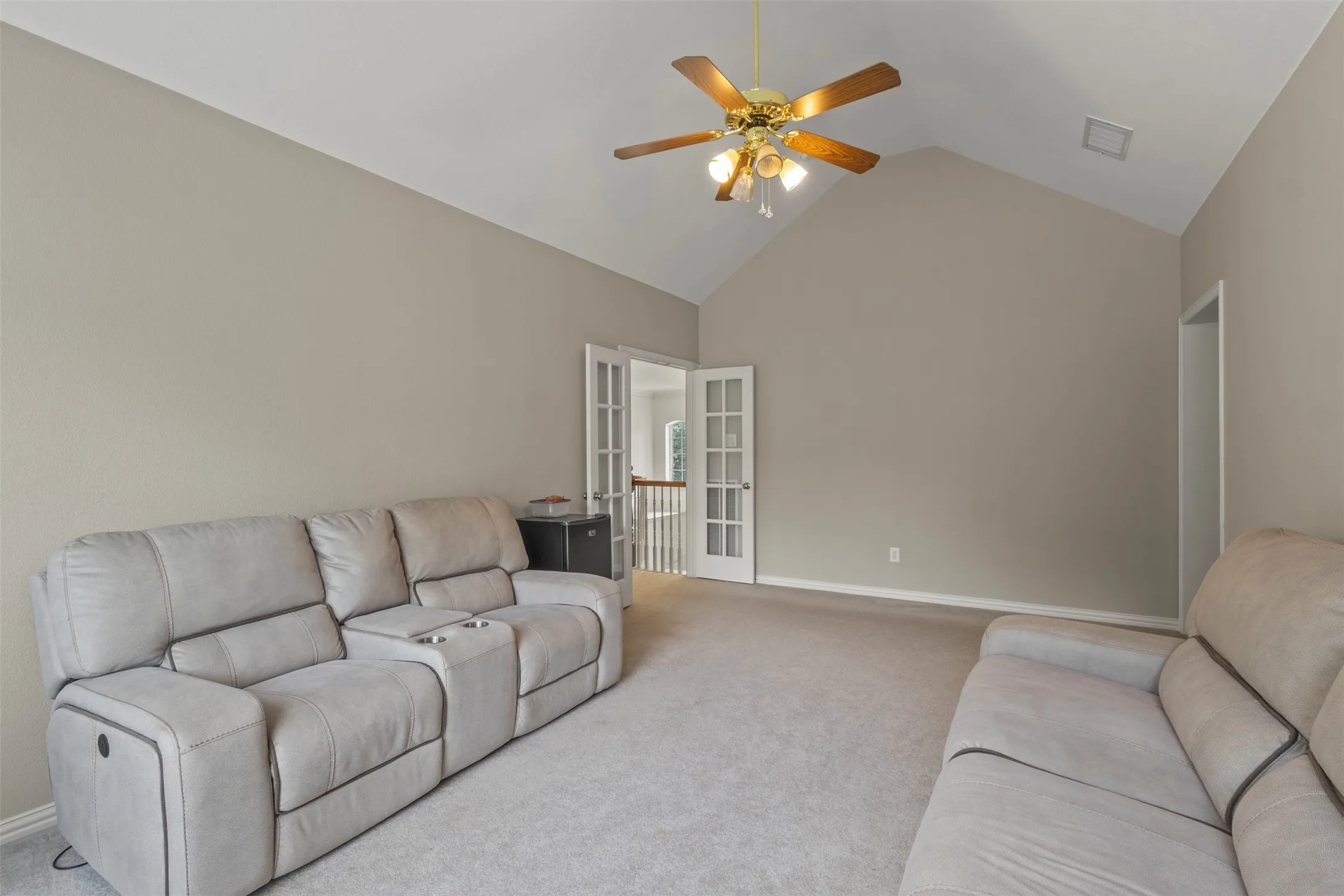 Vaulted ceiling with a ceiling fan, neutral wall paint, and carpet flooring