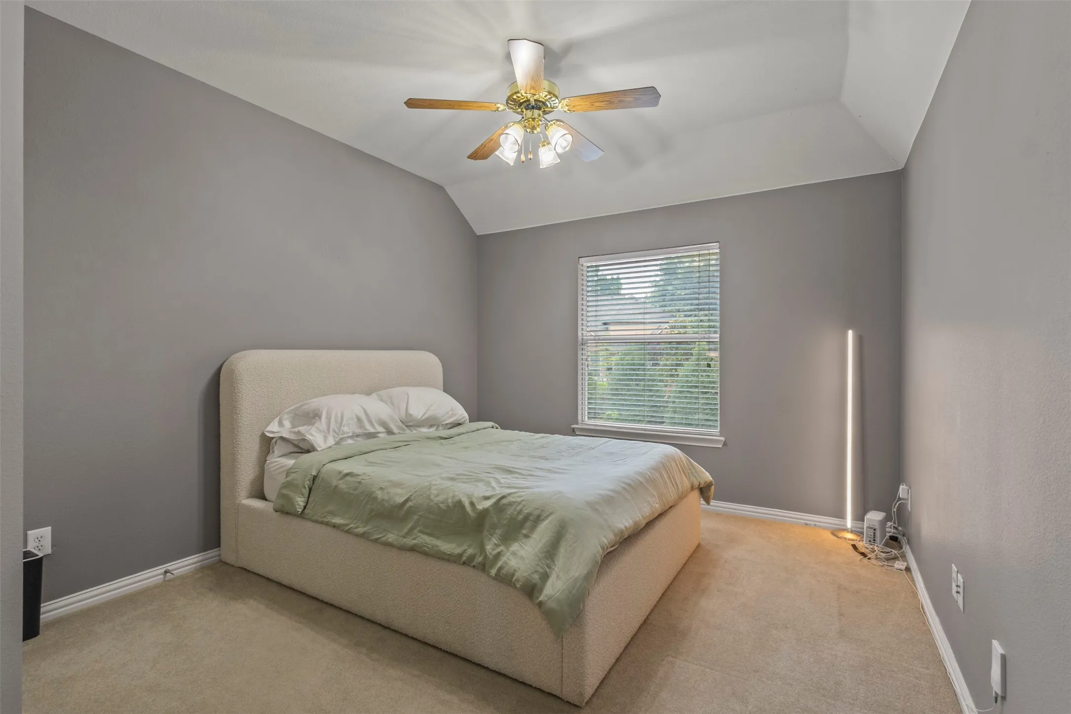 Carpeted room featuring a window with blinds, ceiling fan with lighting, and vaulted ceiling