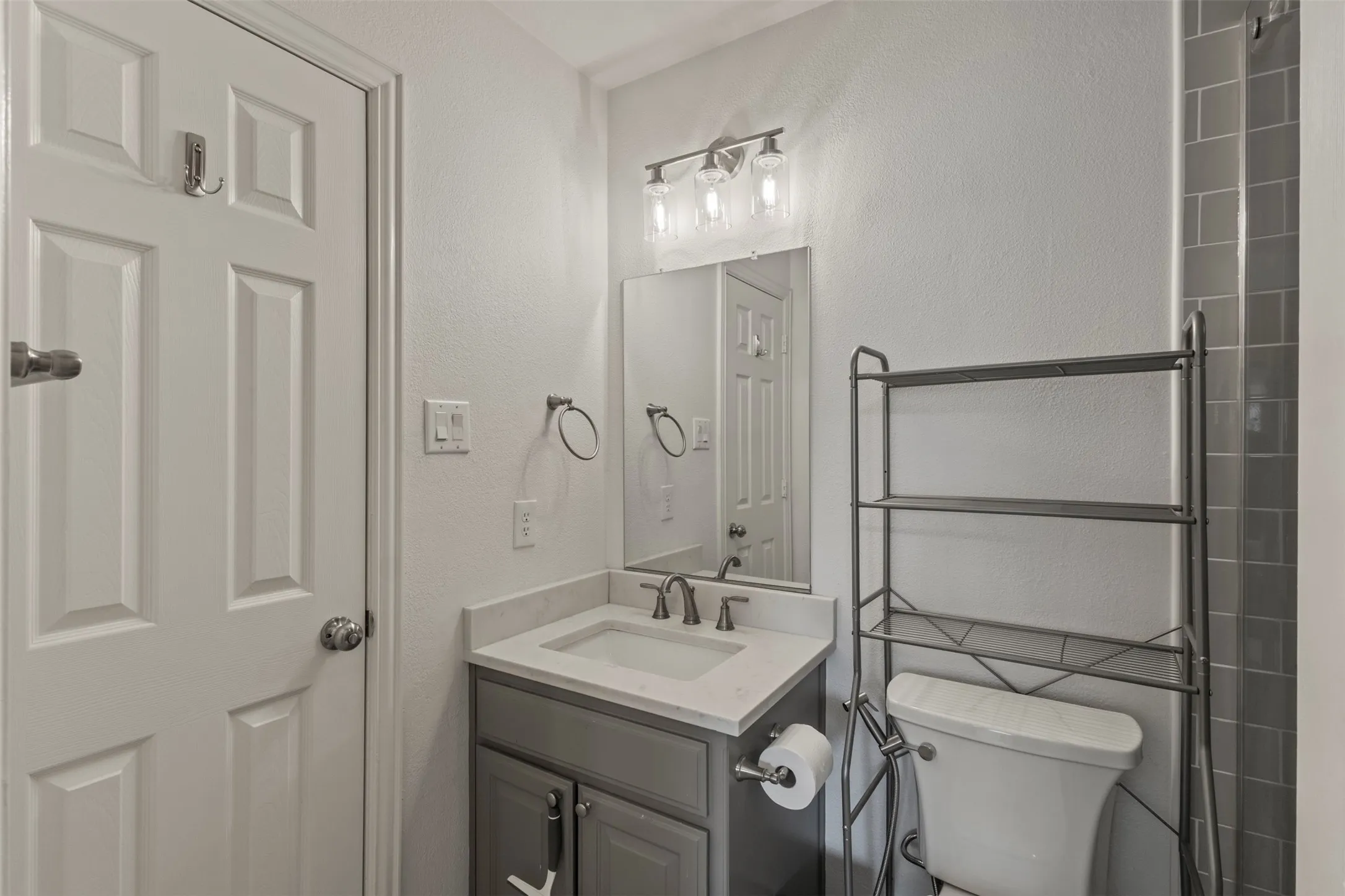 Vanity with integrated sink and chrome faucet, rectangular mirror, and three-light vanity bar
