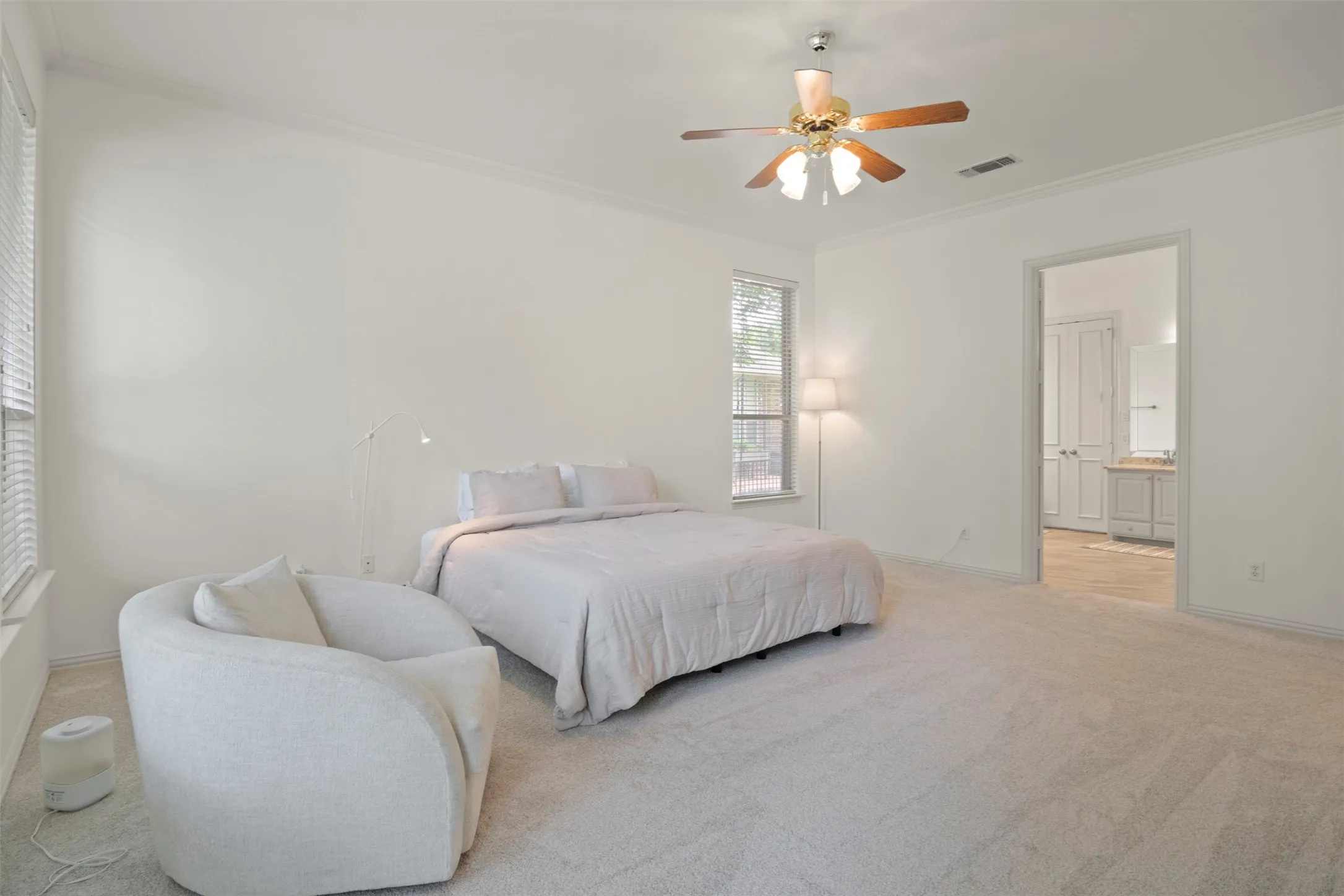 Spacious room featuring neutral carpeting, a ceiling fan, crown molding, and a window with blinds
