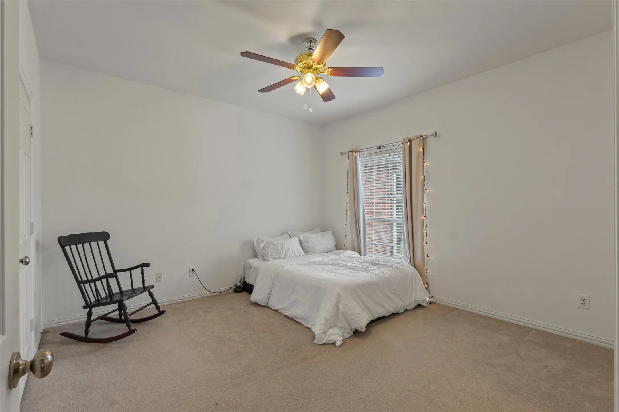 Carpeted room featuring a ceiling fan with integrated lighting, a window with blinds, and white walls