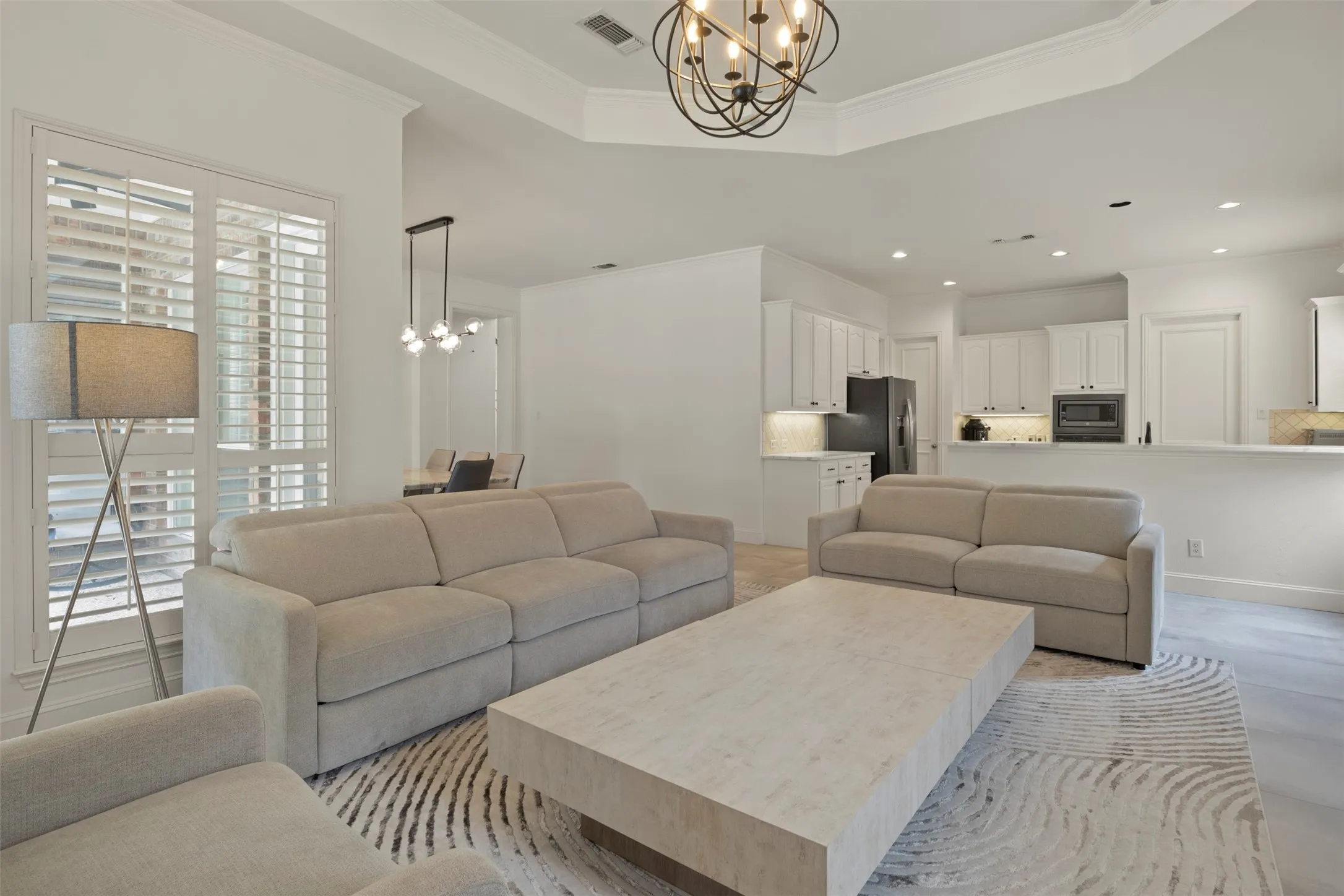 Recessed lighting, crown molding, plantation shutters, built-in kitchen cabinetry, and a tray ceiling