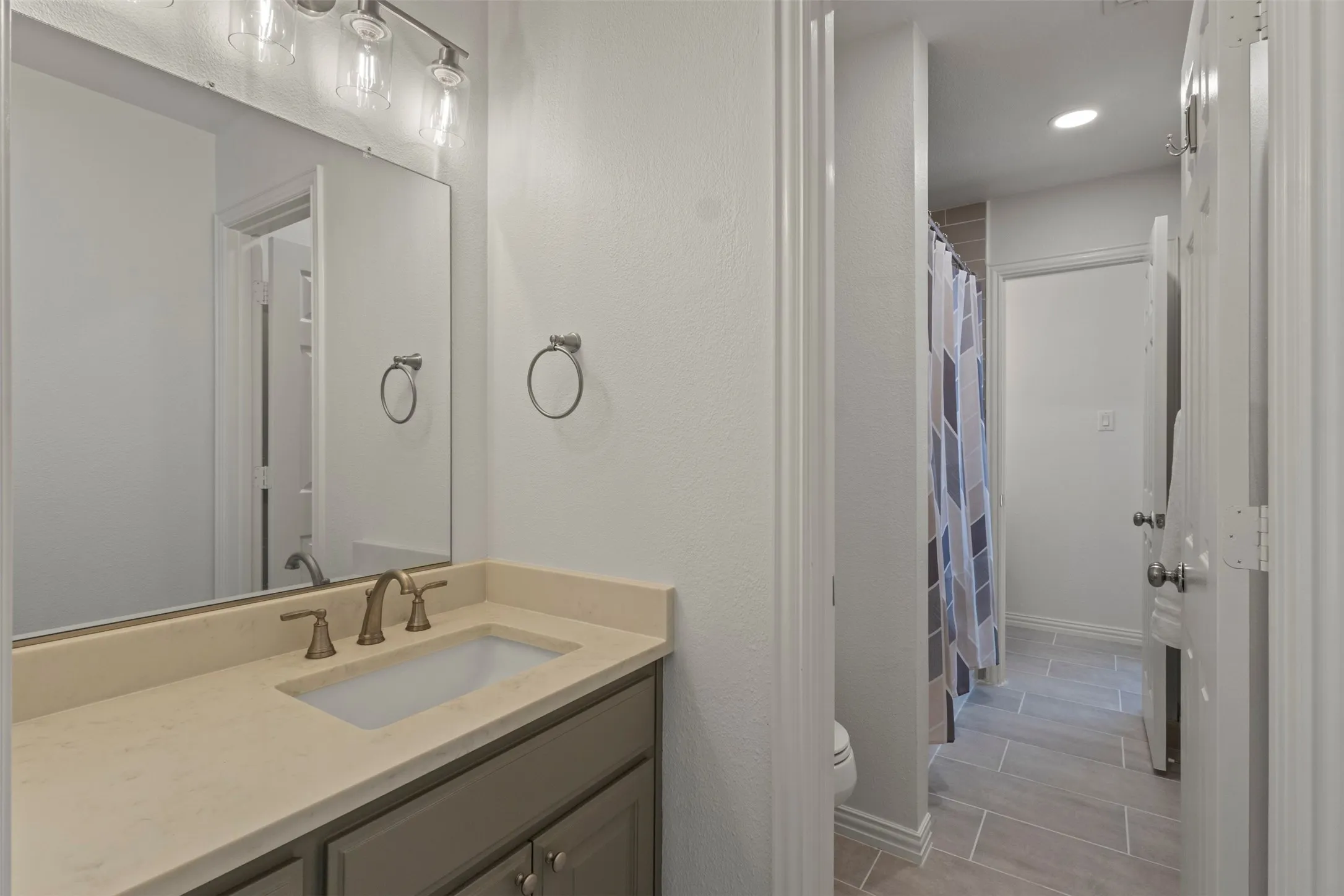Bathroom featuring a single vanity with an integrated sink, brushed nickel faucet, and a wall-mounted light fixture
