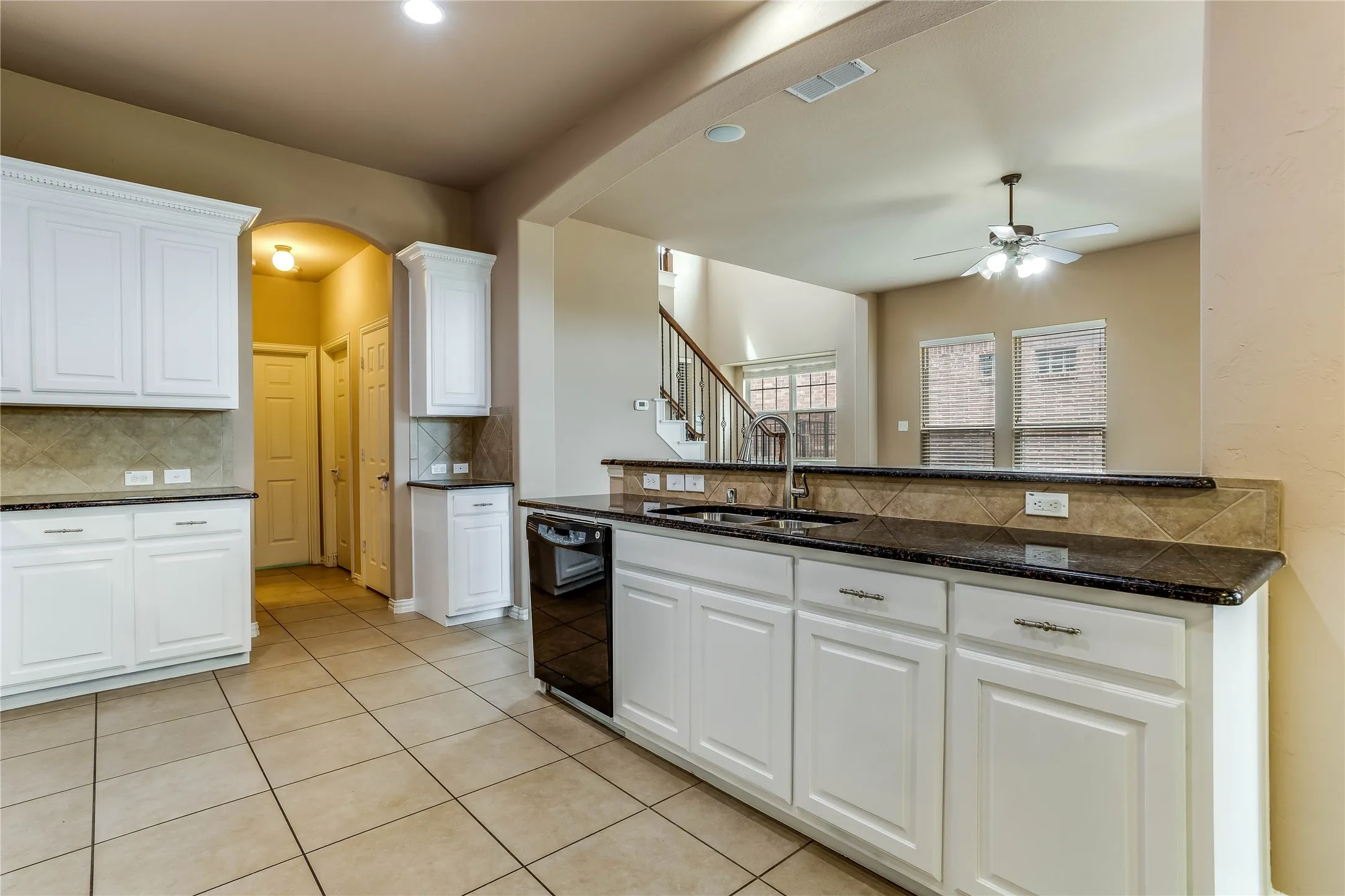 Kitchen featuring white cabinetry, dark countertops, a tile backsplash, and tile flooring