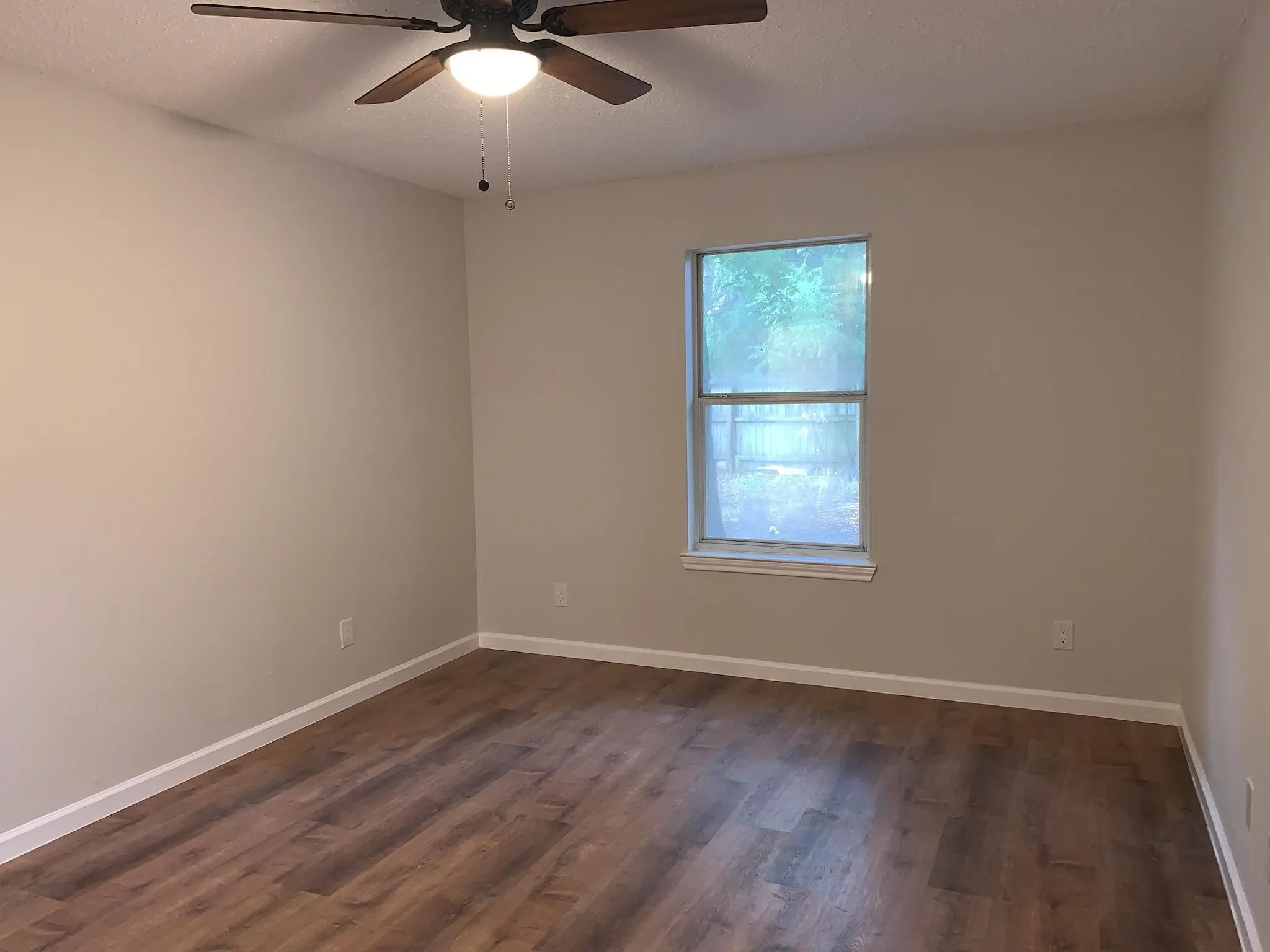 Wood-finish flooring, neutral wall tones, and a window with natural illumination
