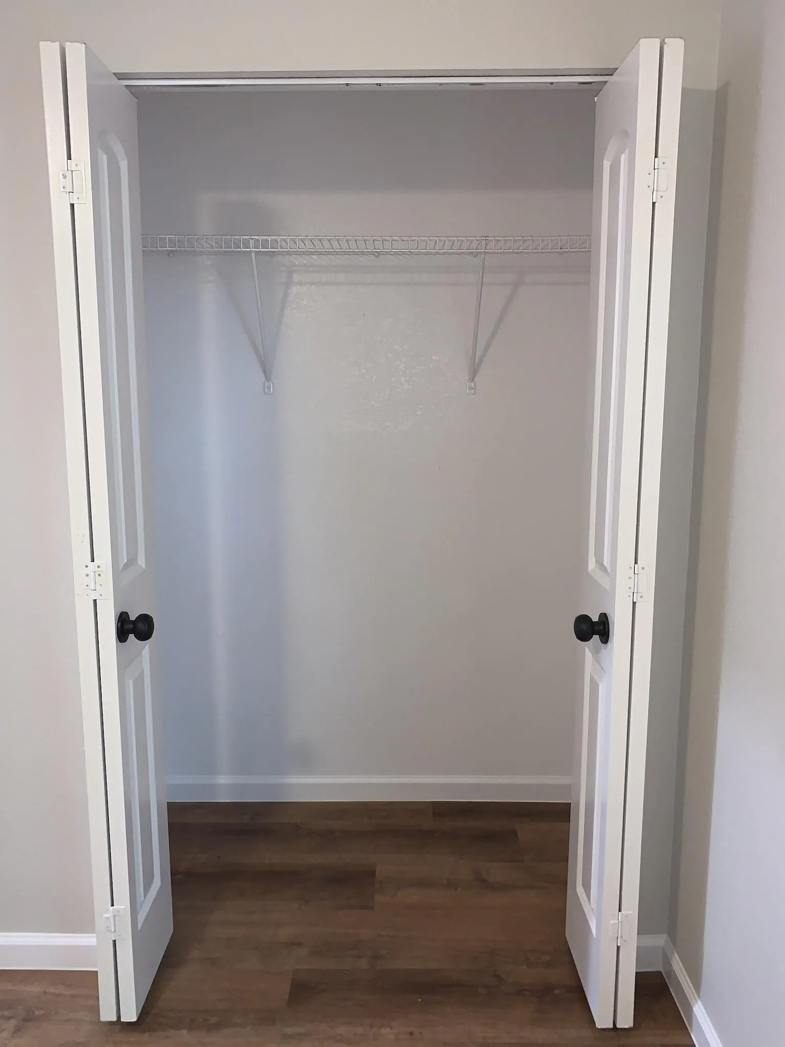 Closet featuring bifold doors with black hardware, wood-finish flooring, and a wire shelving system