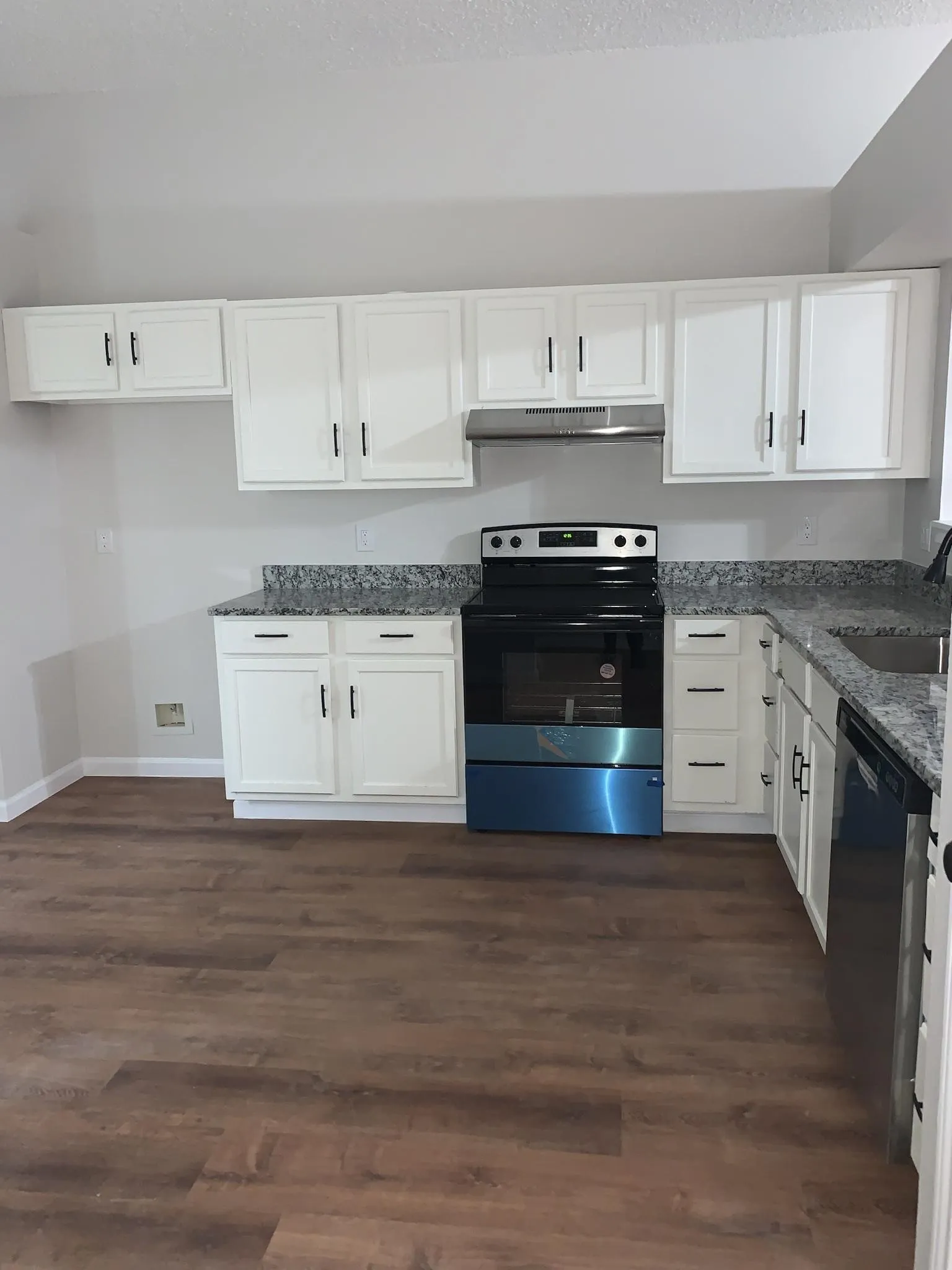 White cabinetry, stainless steel range, built-in dishwasher, wood-finish flooring, and light-toned countertops